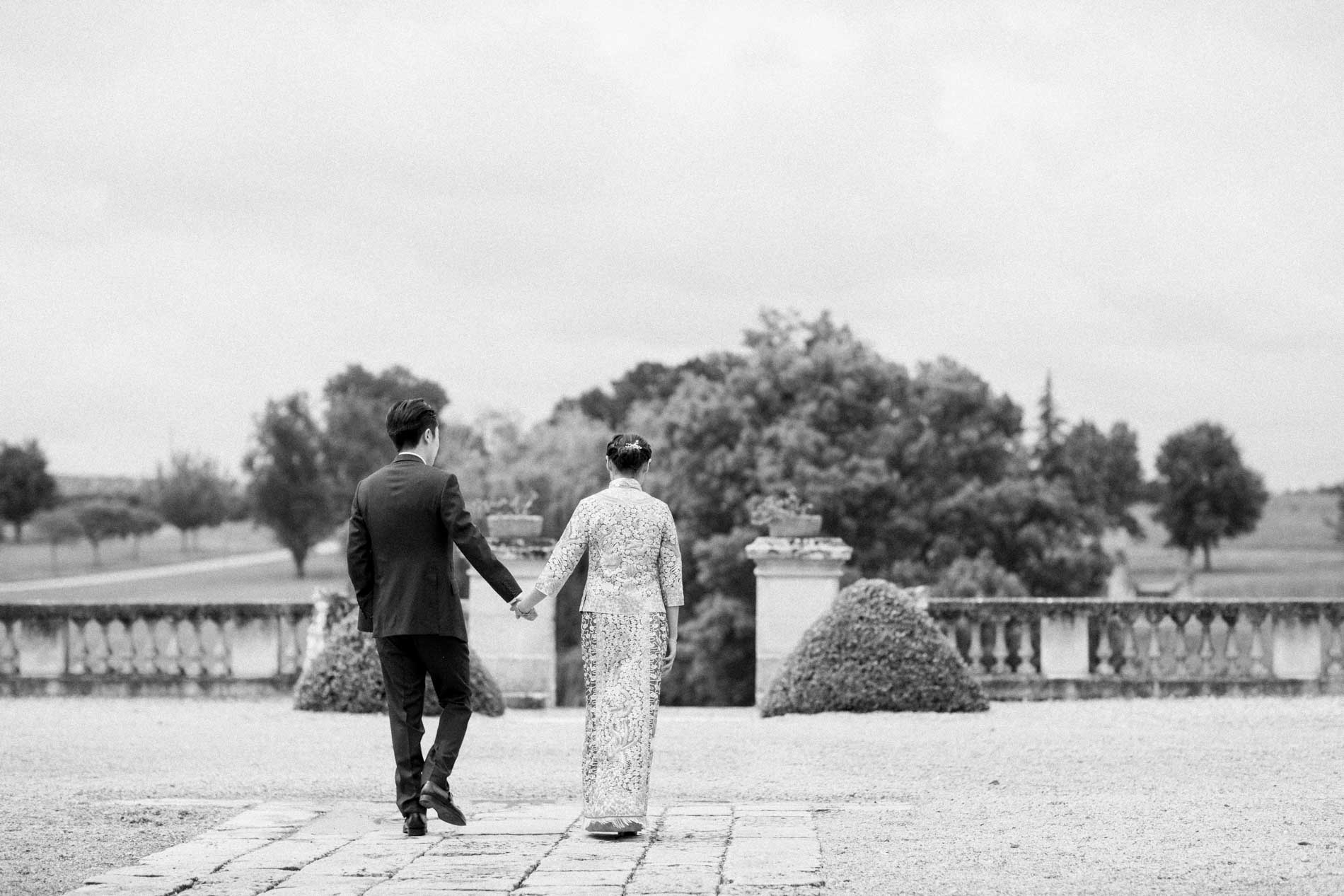 The couple from behind, hand in hand on the balustraded terrace, in black and white