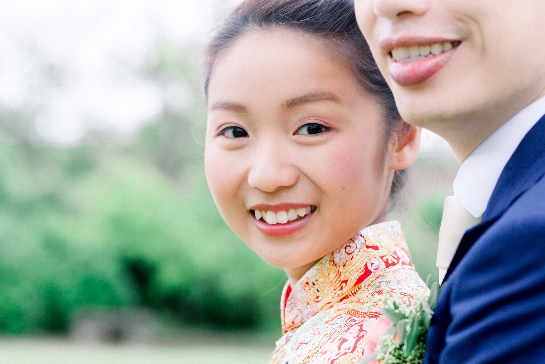 The bride smiling in her embroidered outfit, cheek to cheek with the groom