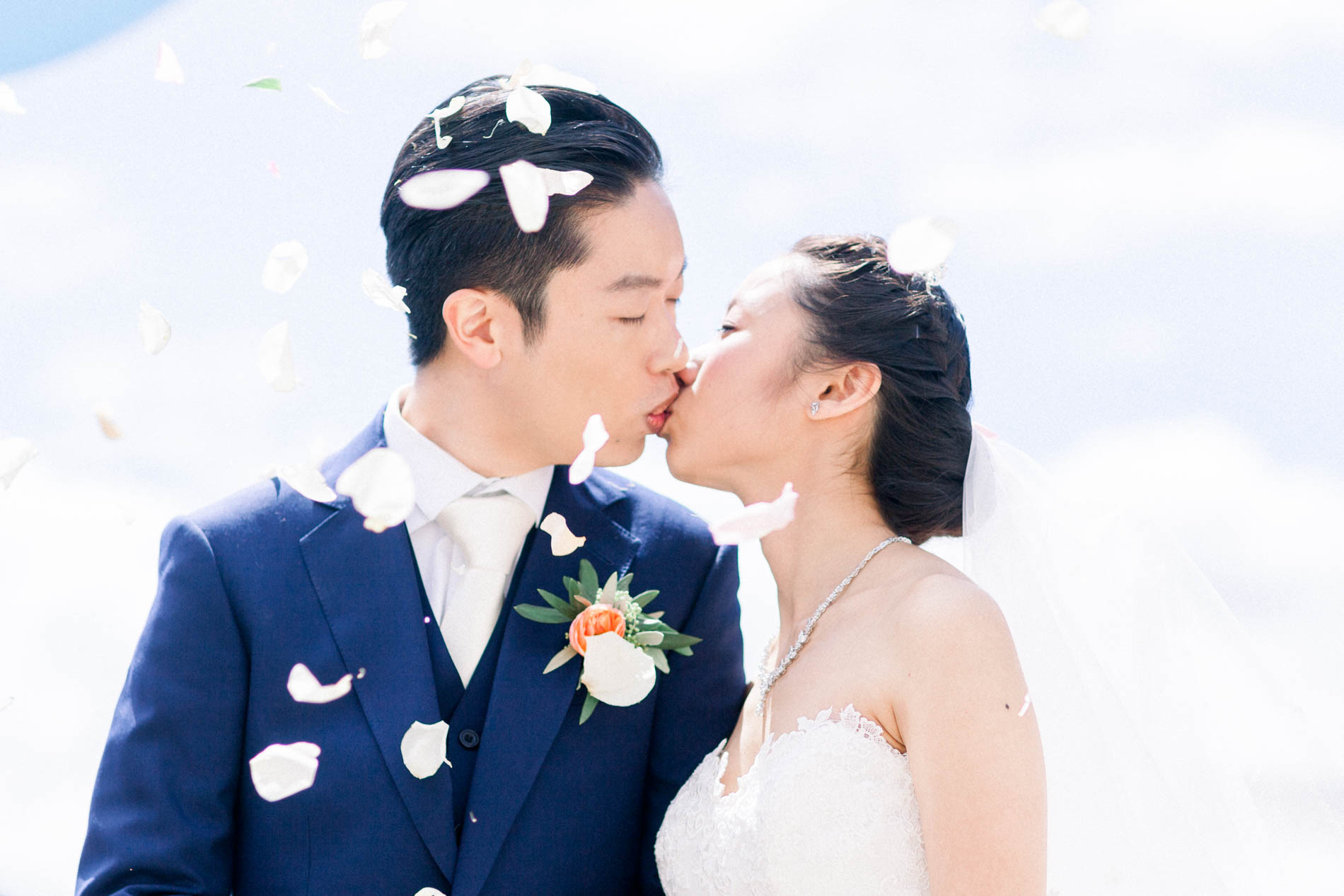 The couple kissing under a shower of petals after the ceremony
