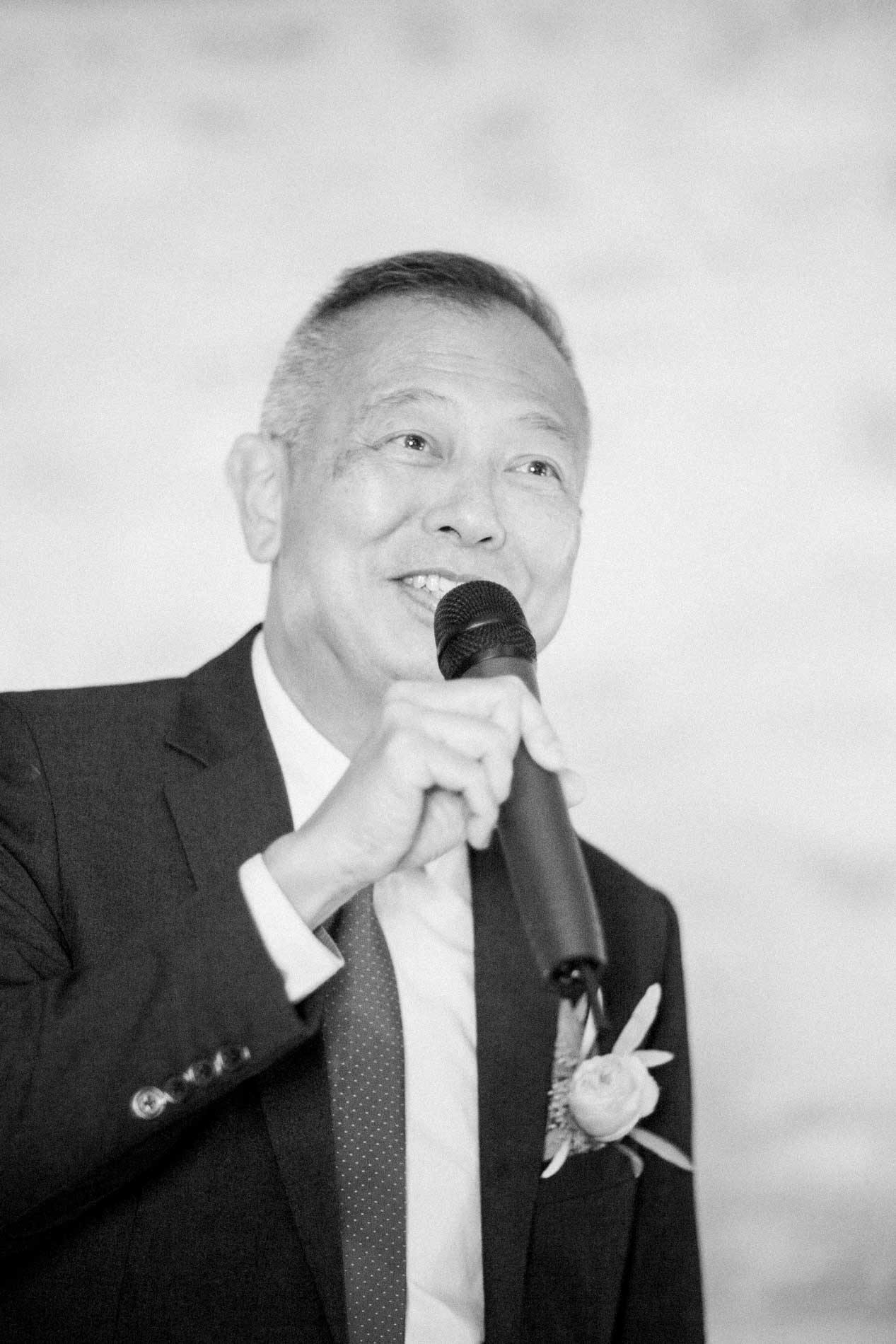 A guest giving a speech into the microphone during the evening, in black and white