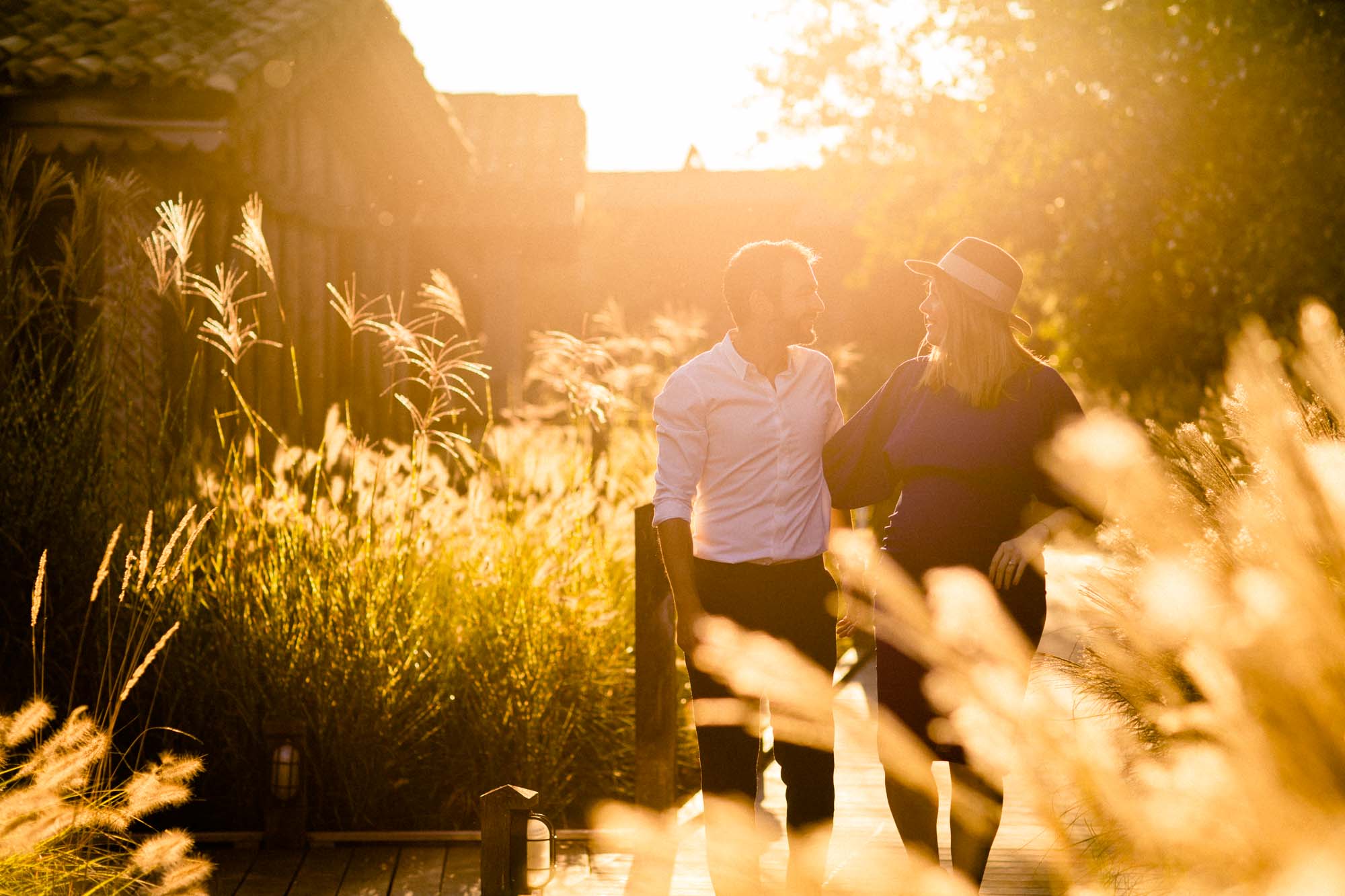 The couple hand in hand, backlit by golden evening light