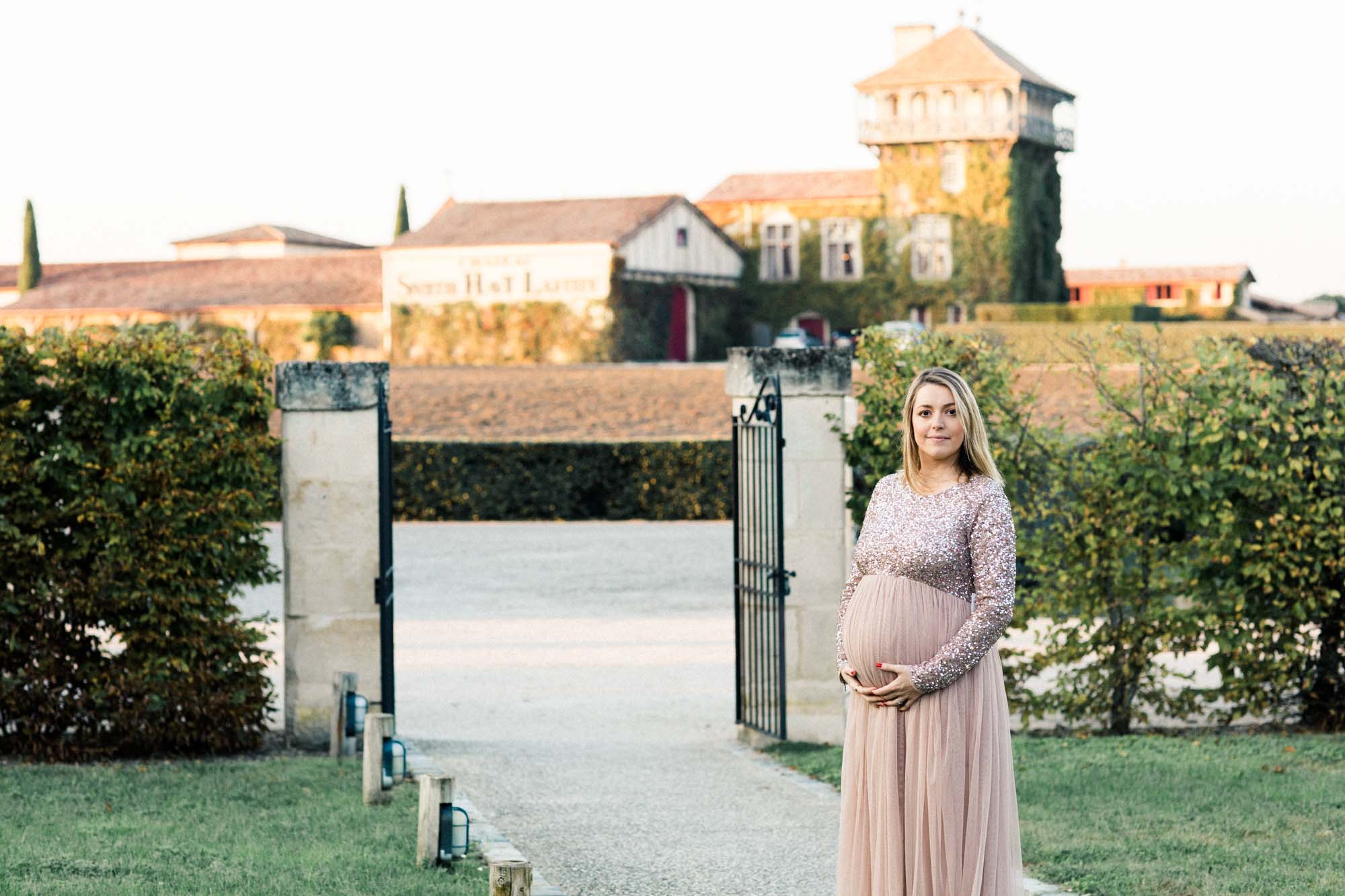 The mother-to-be in a blush tulle gown at the entrance of Château Smith Haut Lafitte
