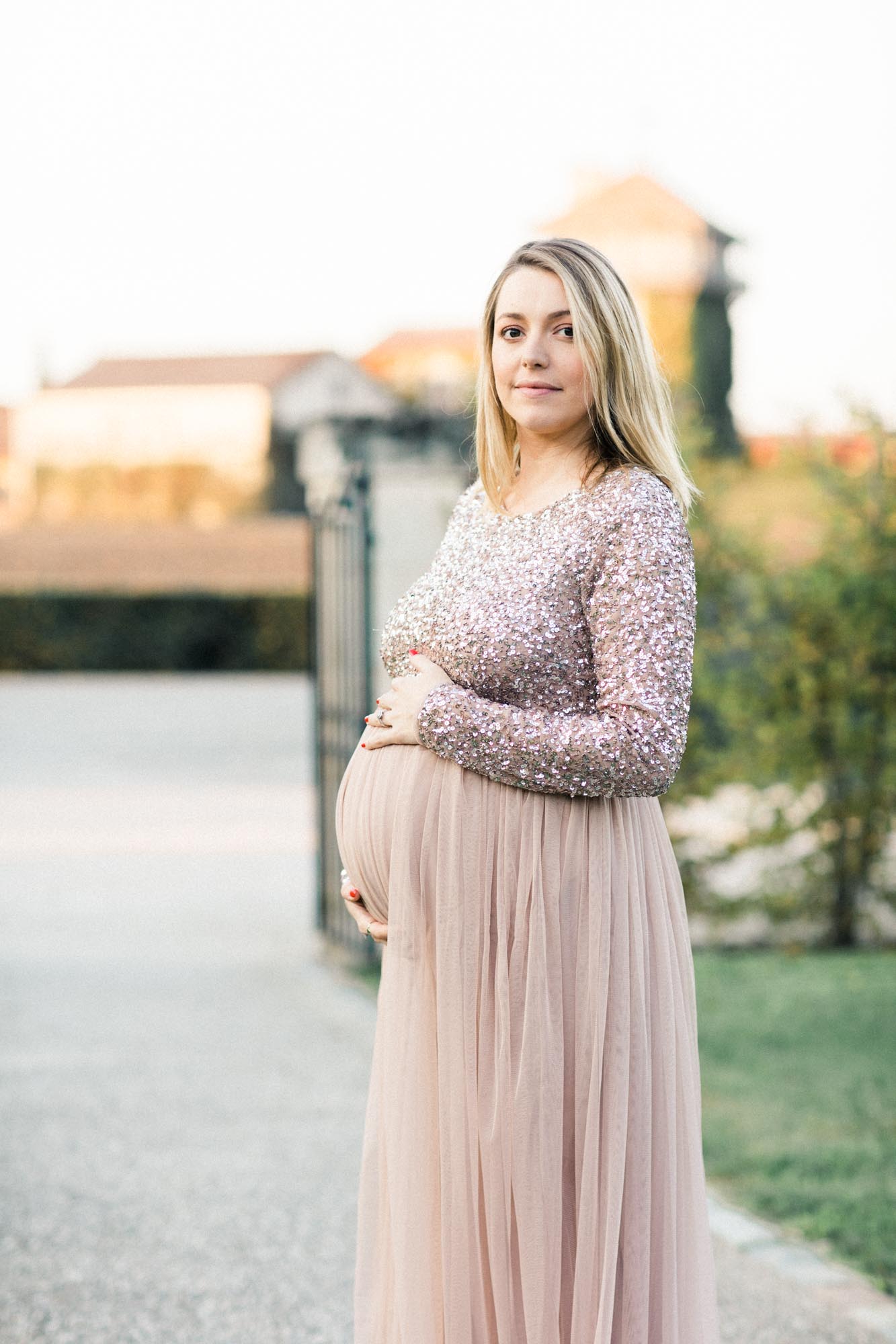 The mother-to-be cradling her bump in the château driveway