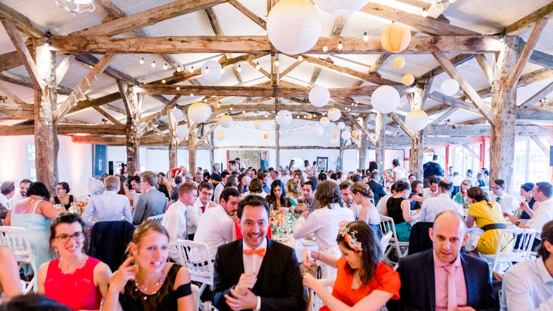 Reception hall with exposed timber roof full of guests at dinner