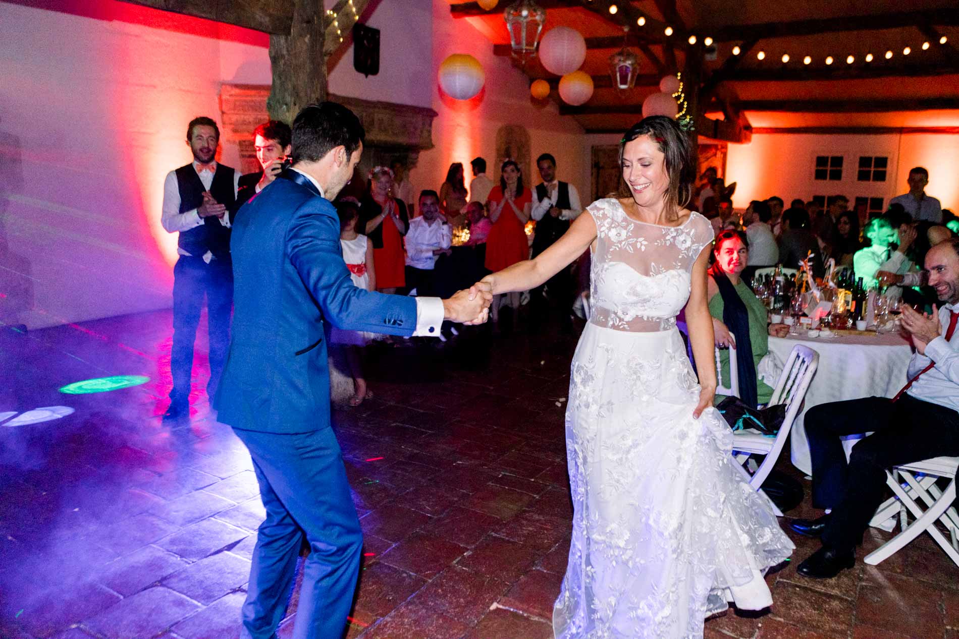 Bride and groom's first dance beneath colourful party lights