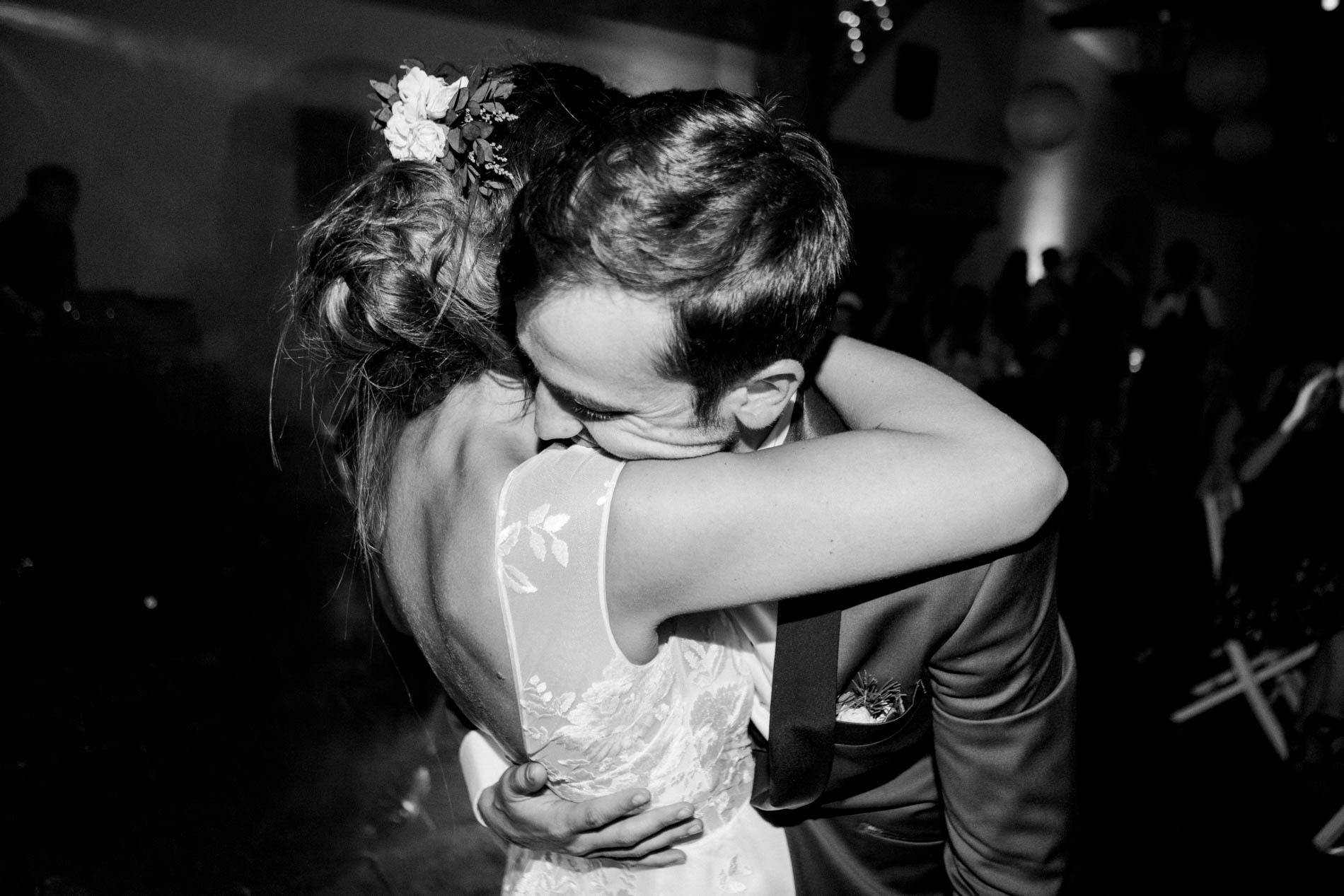 Bride and groom holding each other close during a slow dance, black and white