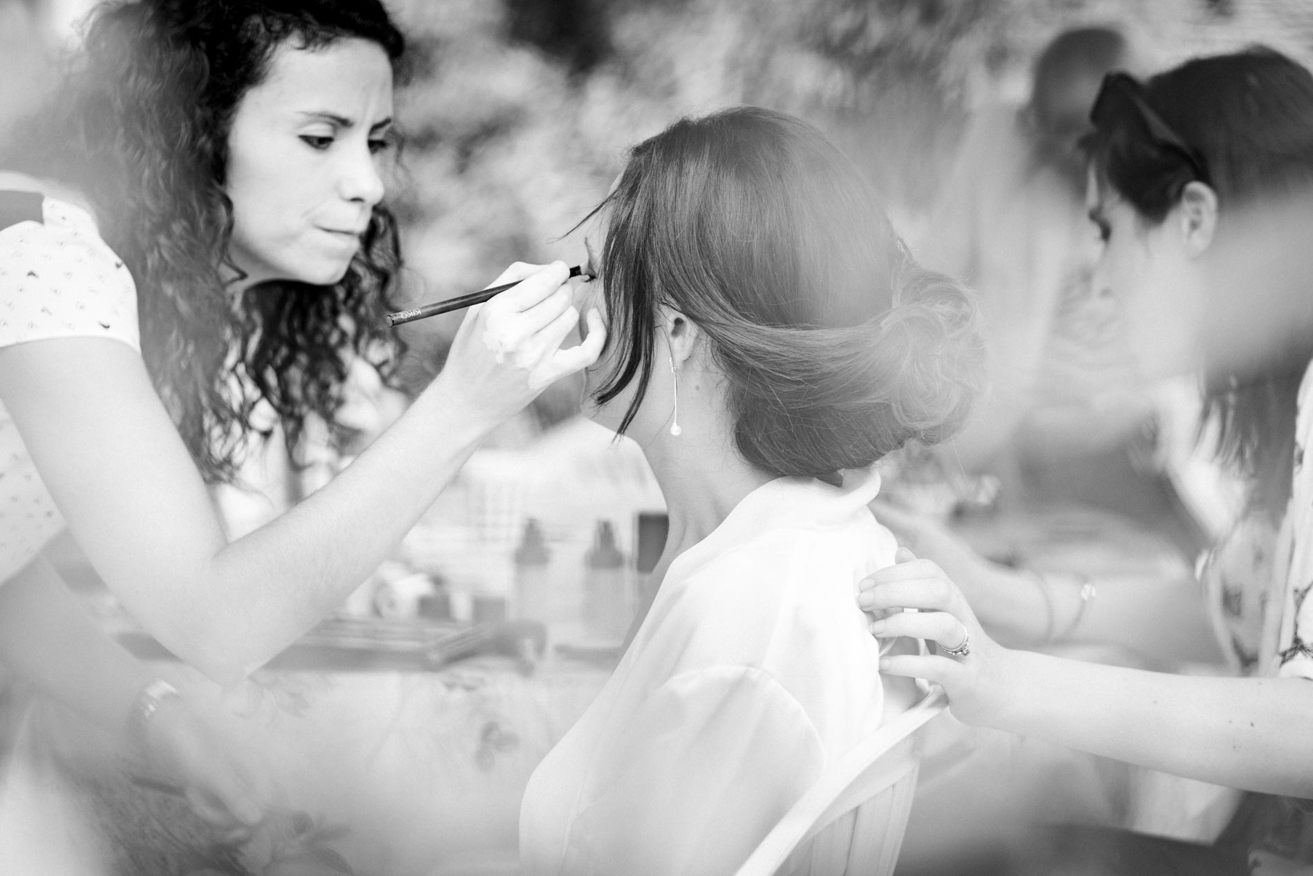 Make-up artist applying the bride's eyeshadow, in black and white