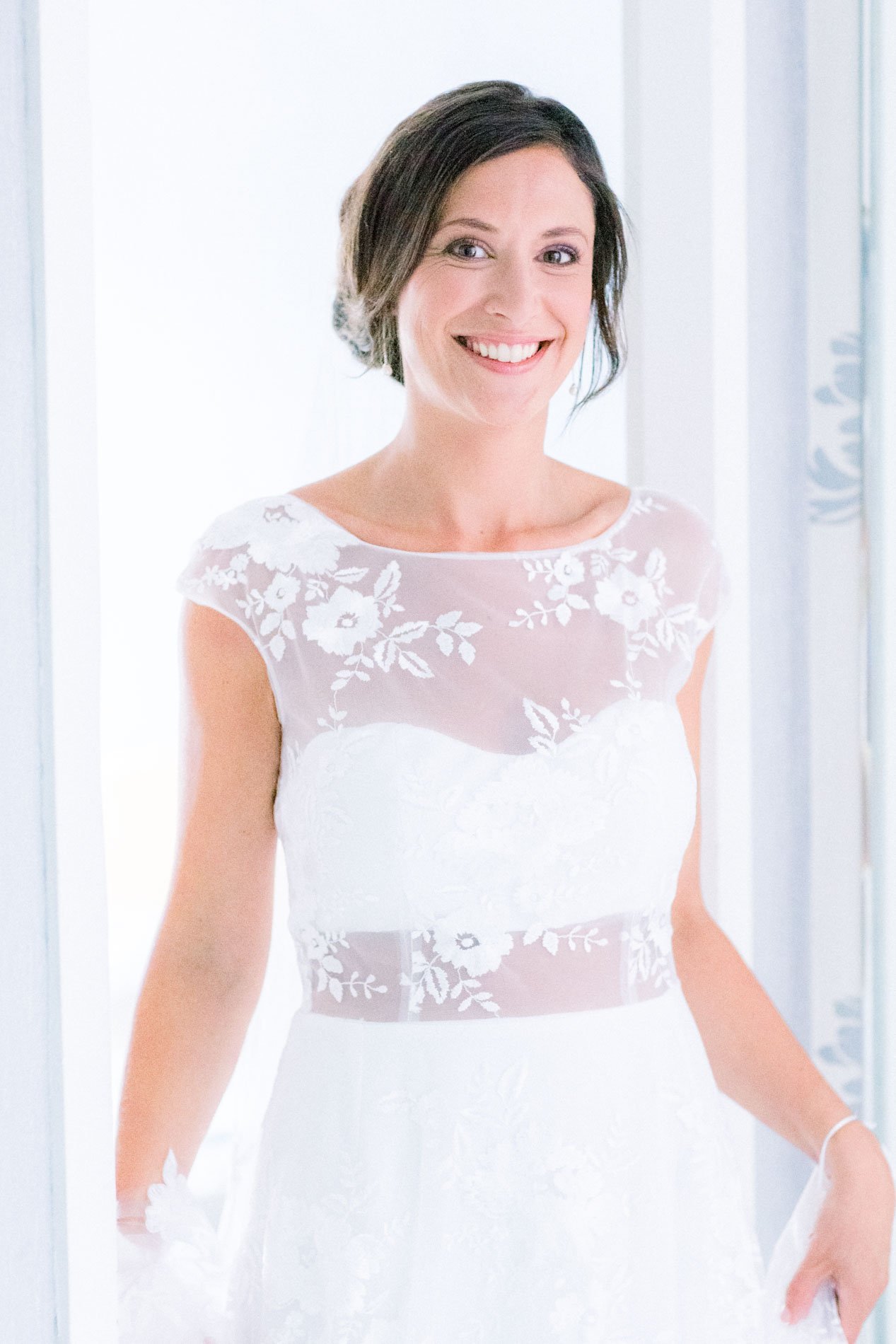 Pearl in her embroidered wedding dress standing in a bright doorway