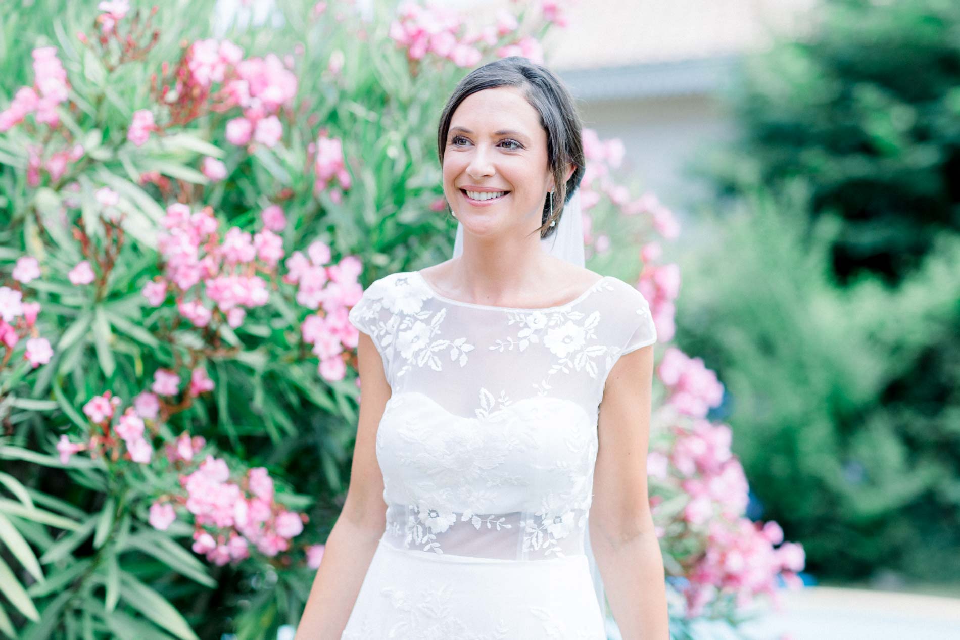 Smiling bride in front of blooming pink oleander bushes