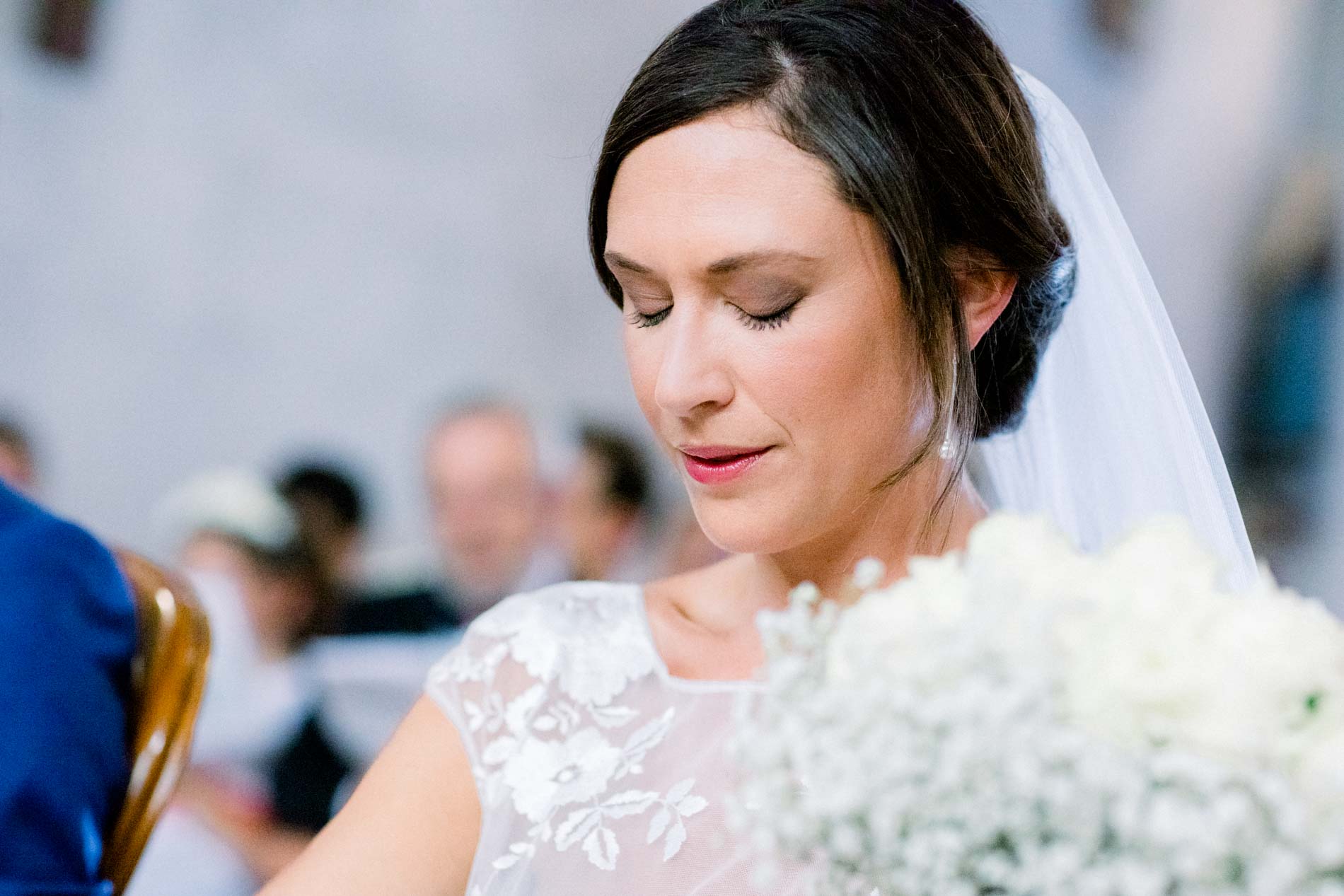 Bride looking down at her baby's breath bouquet during the church service