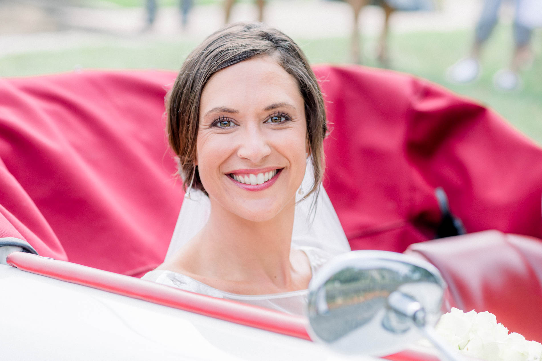 Beaming bride in a vintage convertible with red leather seats