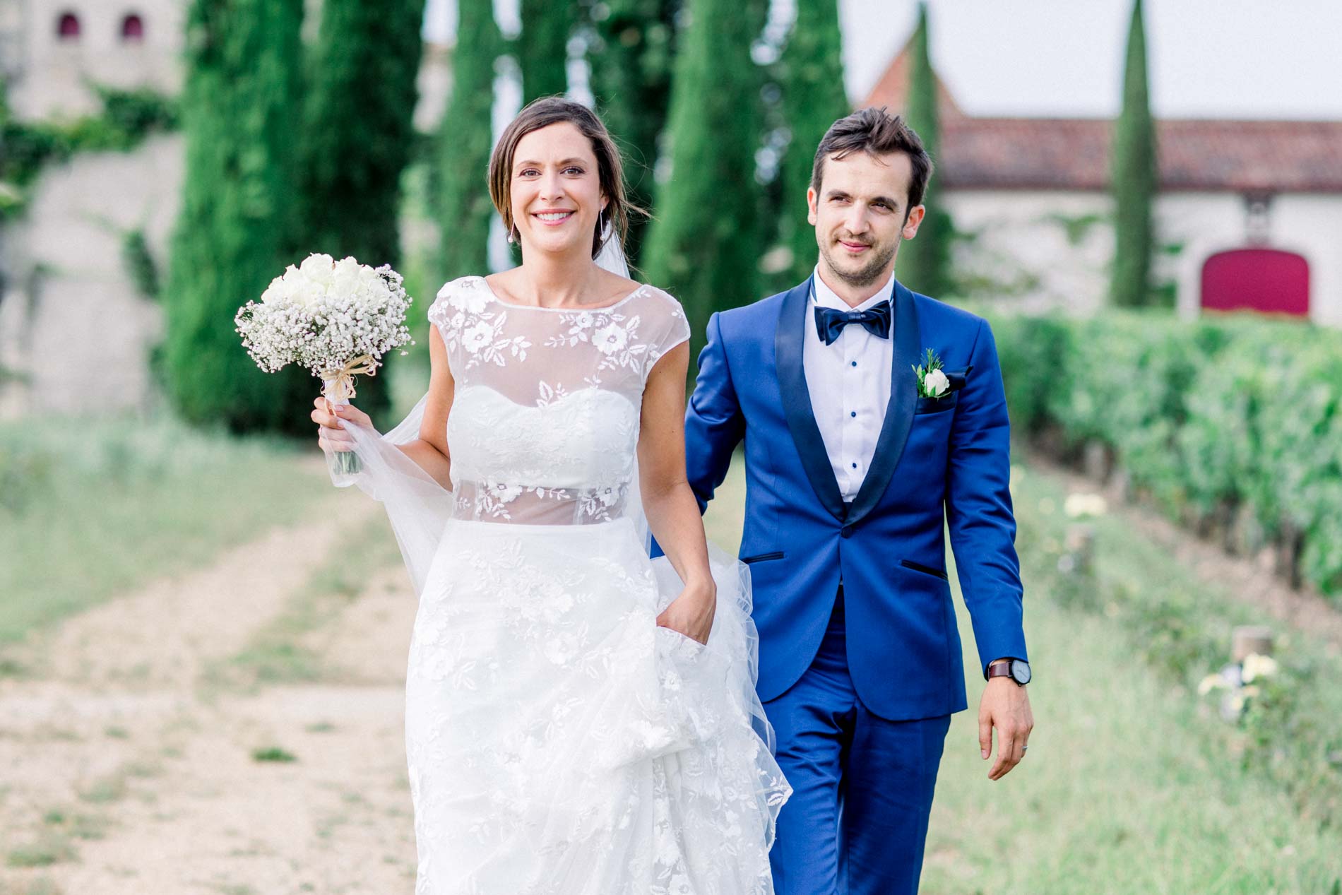 Bride and groom walking between the vine rows at Château Smith Haut Lafitte