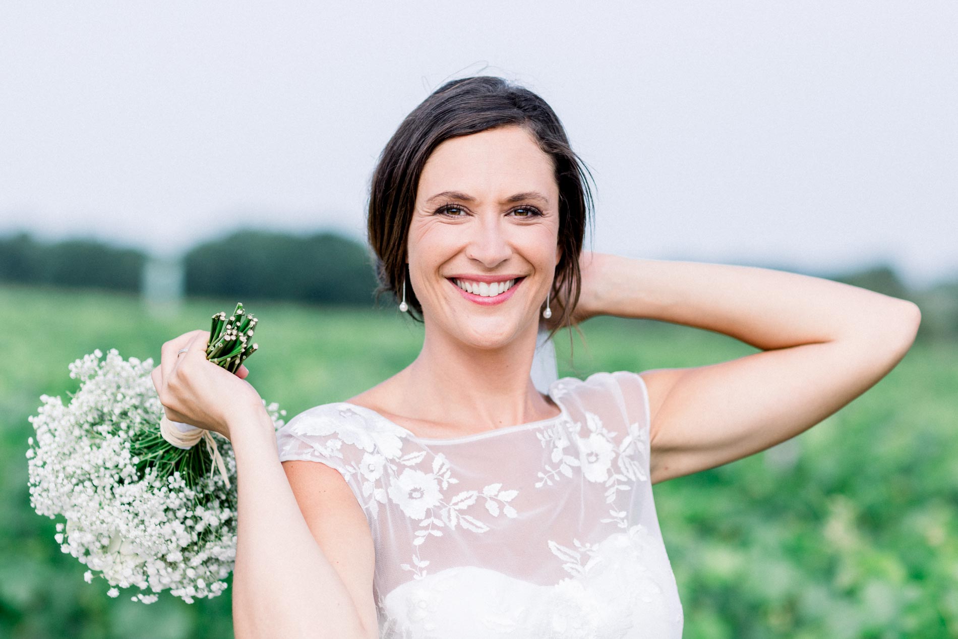 Smiling bride with a hand in her hair among the vines