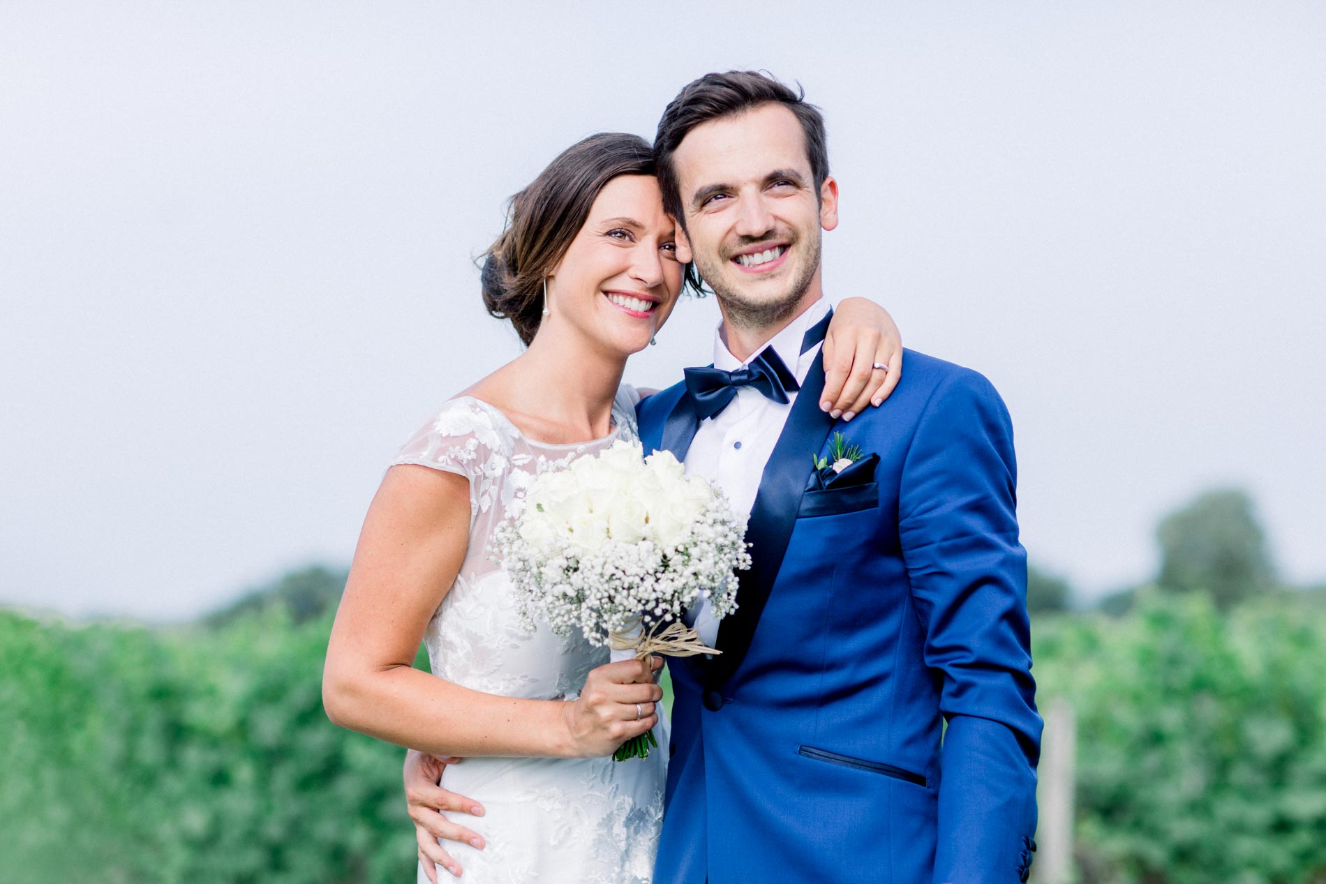 Pearl and Guillaume embracing and smiling among the château vineyards