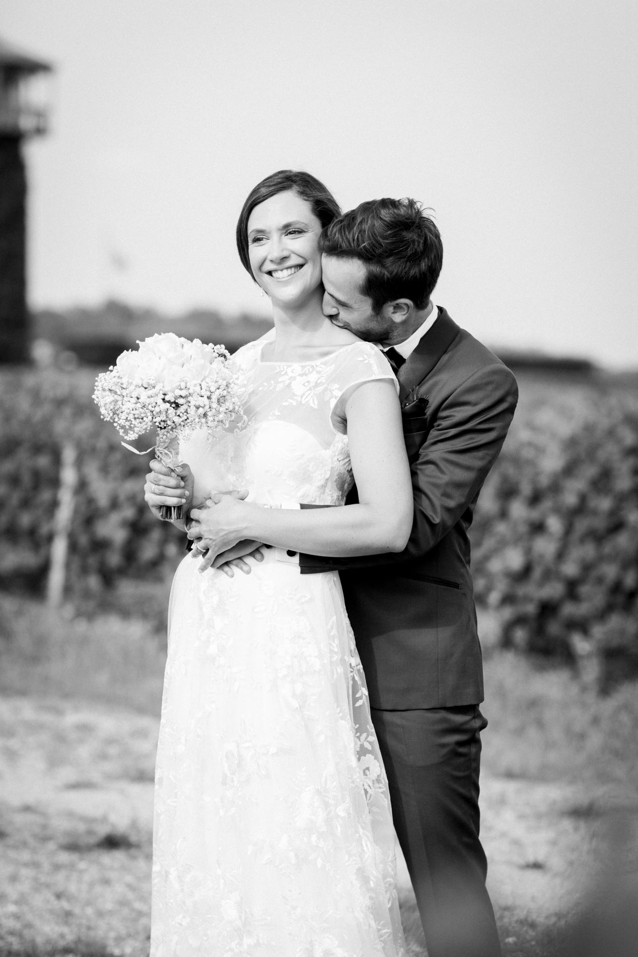 Groom kissing the bride's cheek in the vineyard, black and white