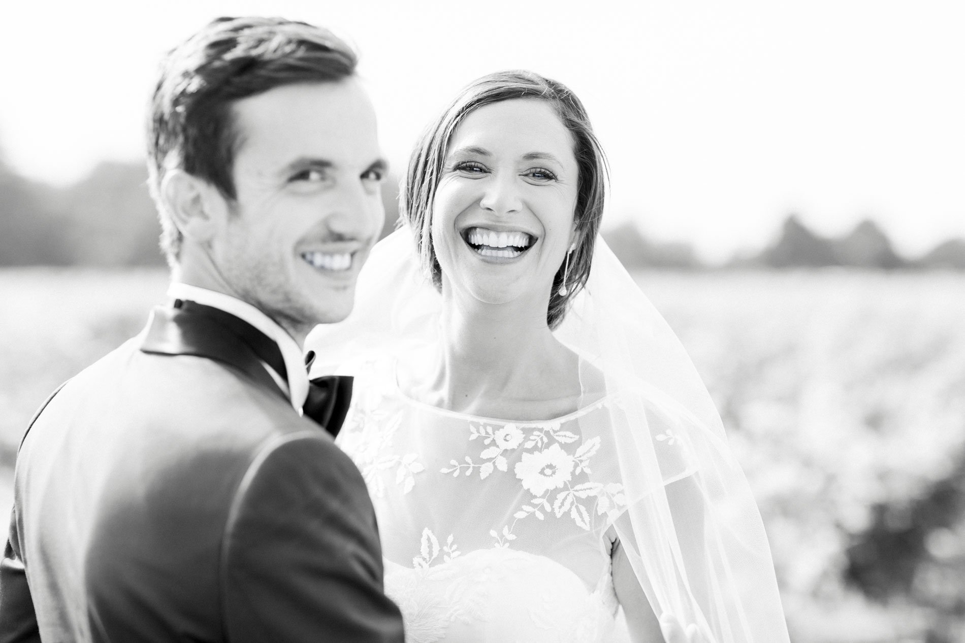 Bride and groom bursting into laughter in the vines, black and white