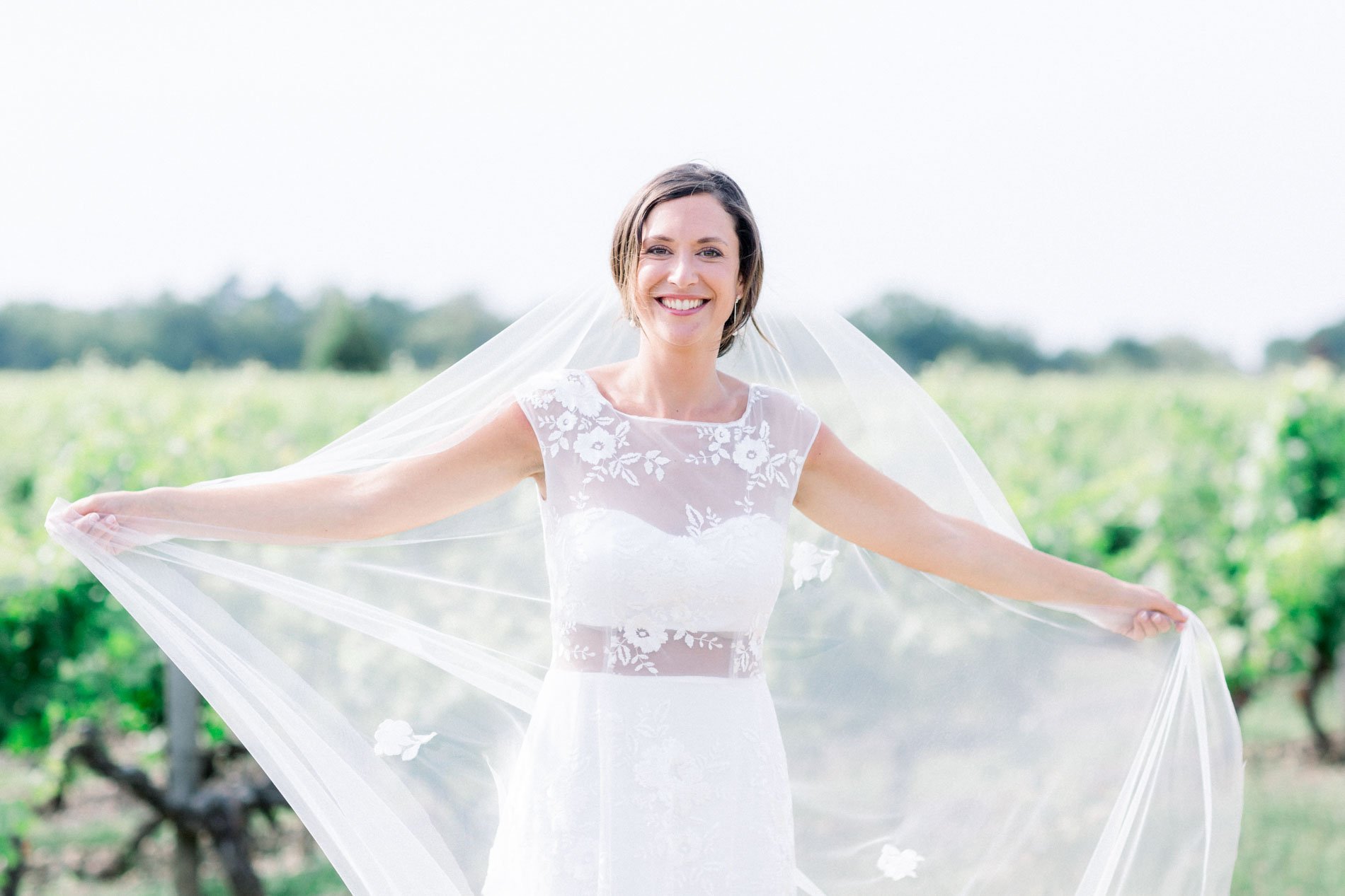 Bride spreading her long veil among the vines of Château Smith Haut Lafitte