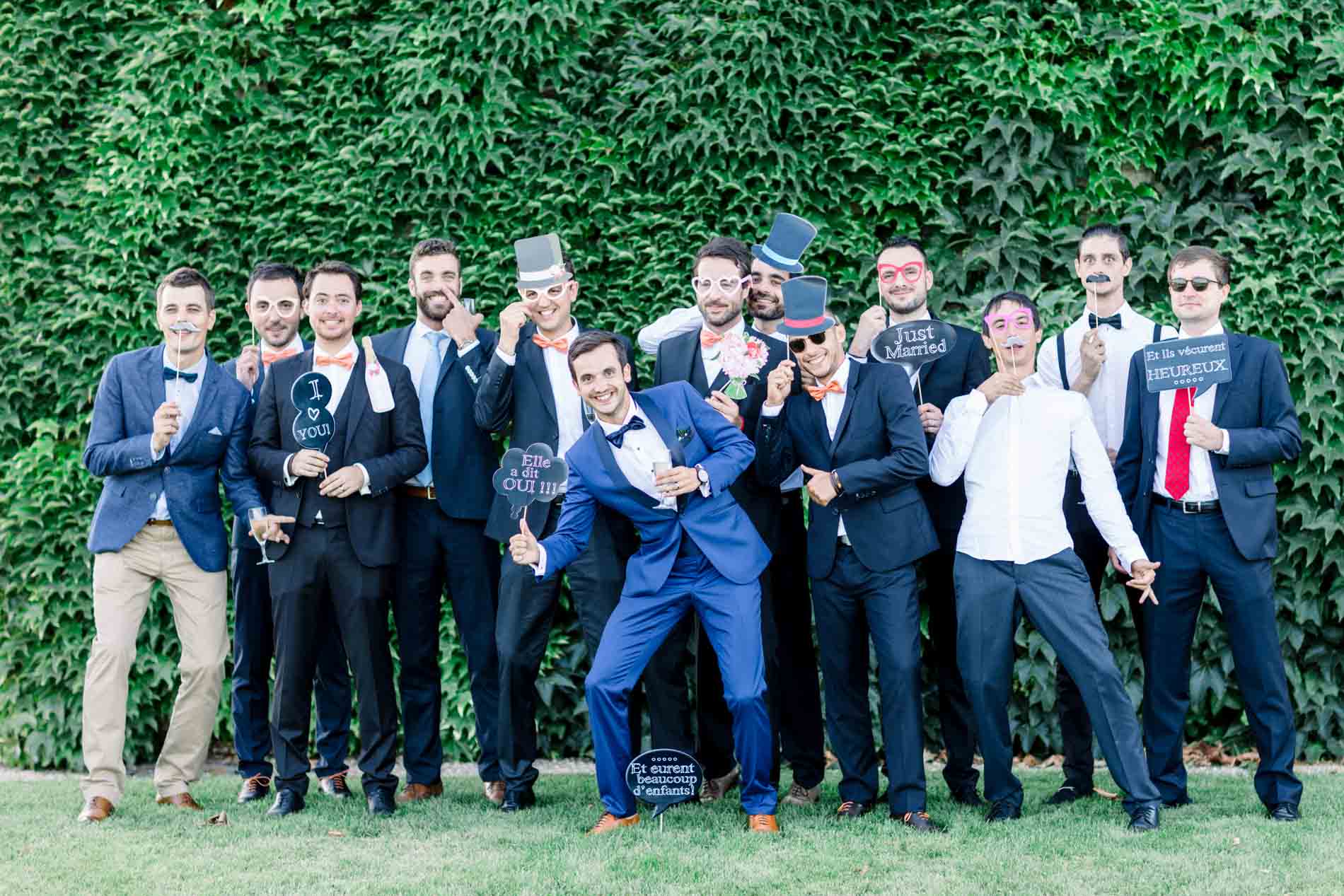 Group photo of the groom and his friends in front of a green wall