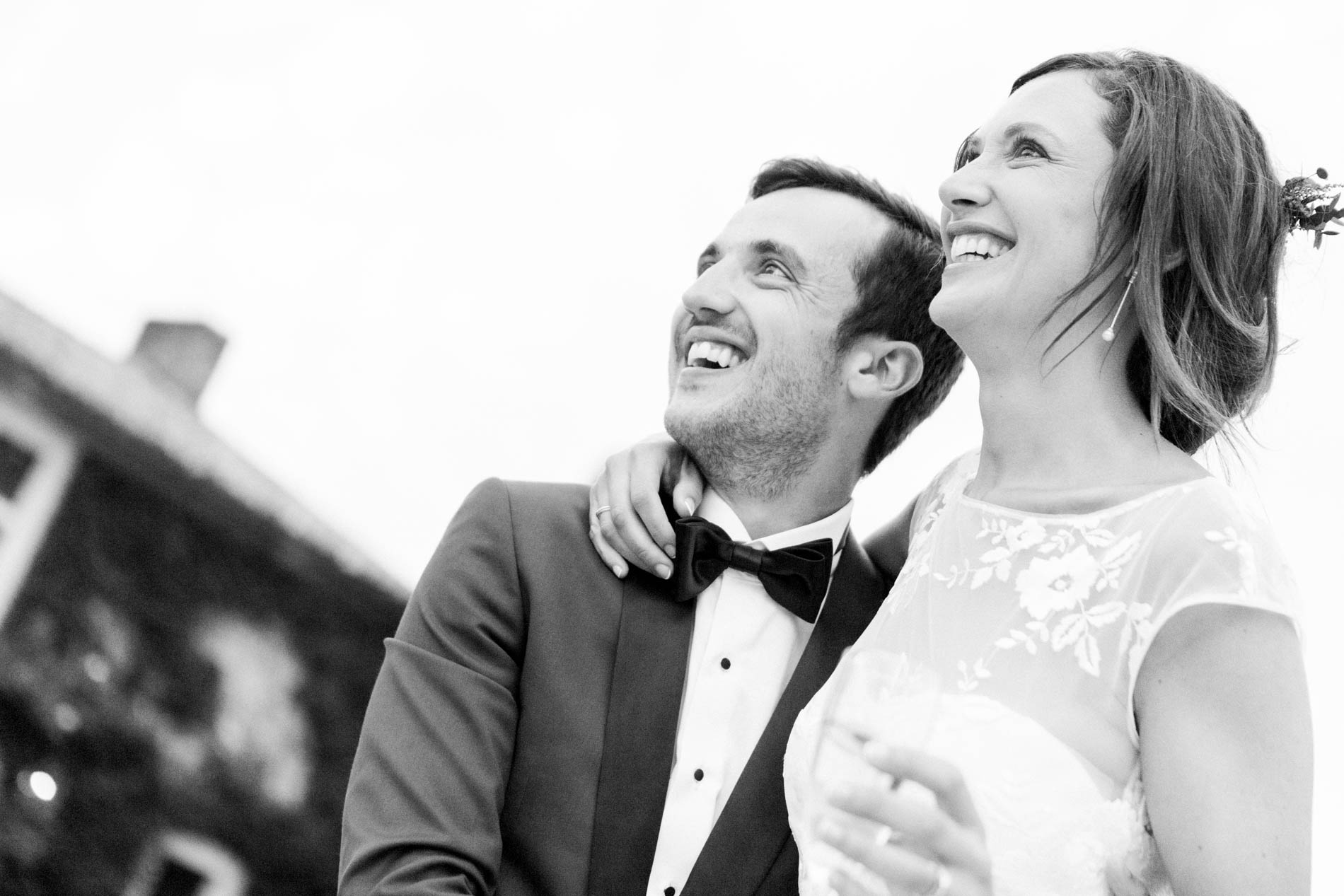 Bride and groom smiling up at the sky, black and white photo