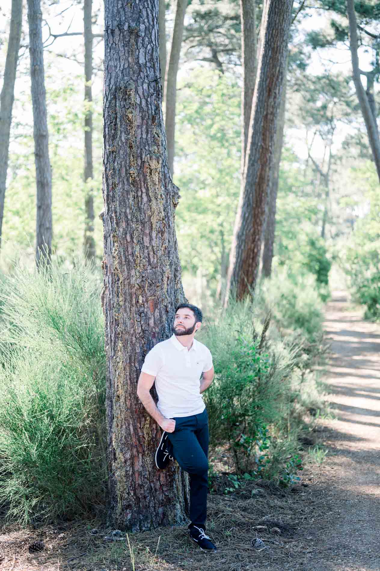 Young man leaning against a pine on a forest path by Arcachon Bay