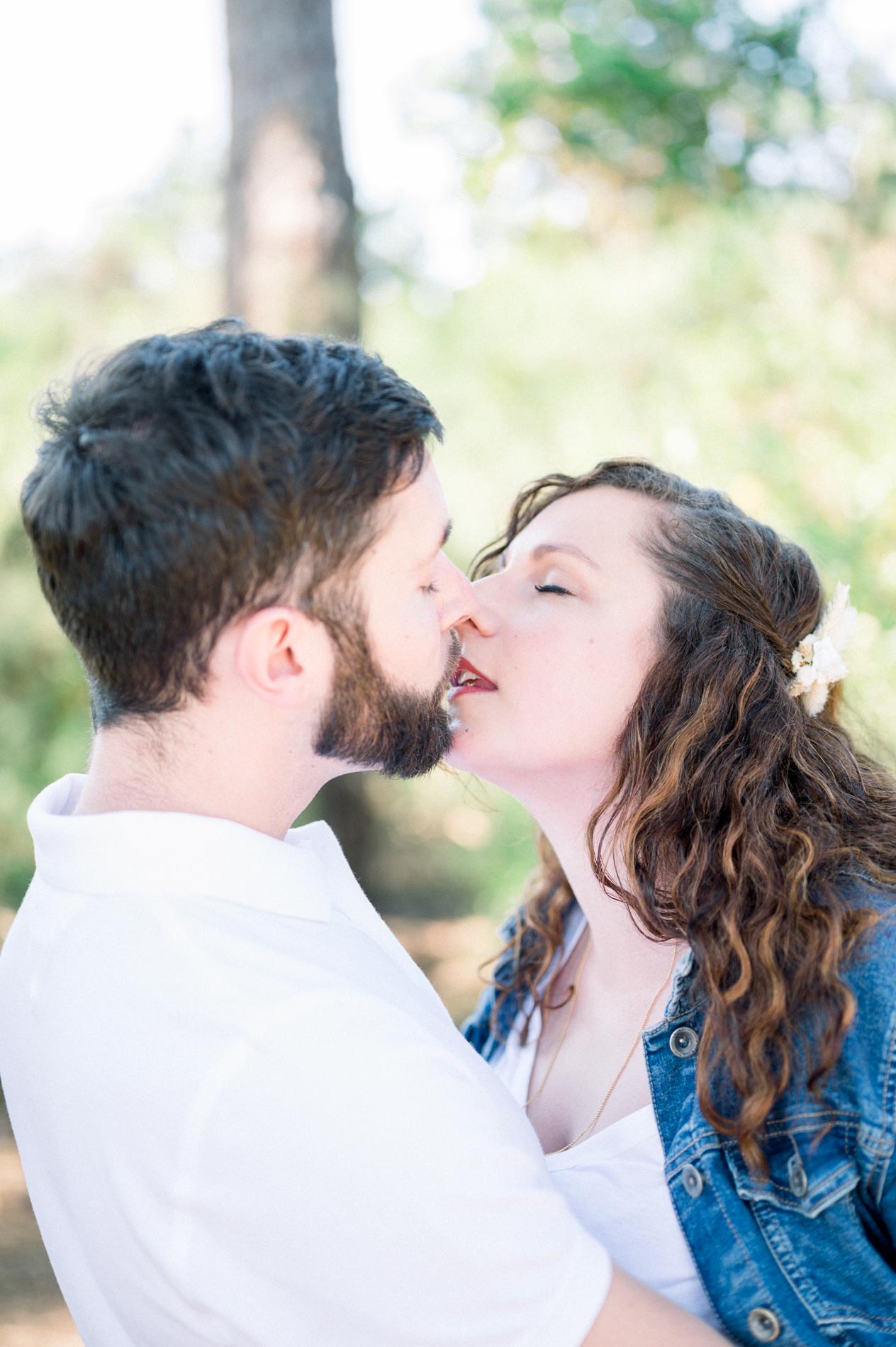 Couple sharing a tender kiss in the soft forest light