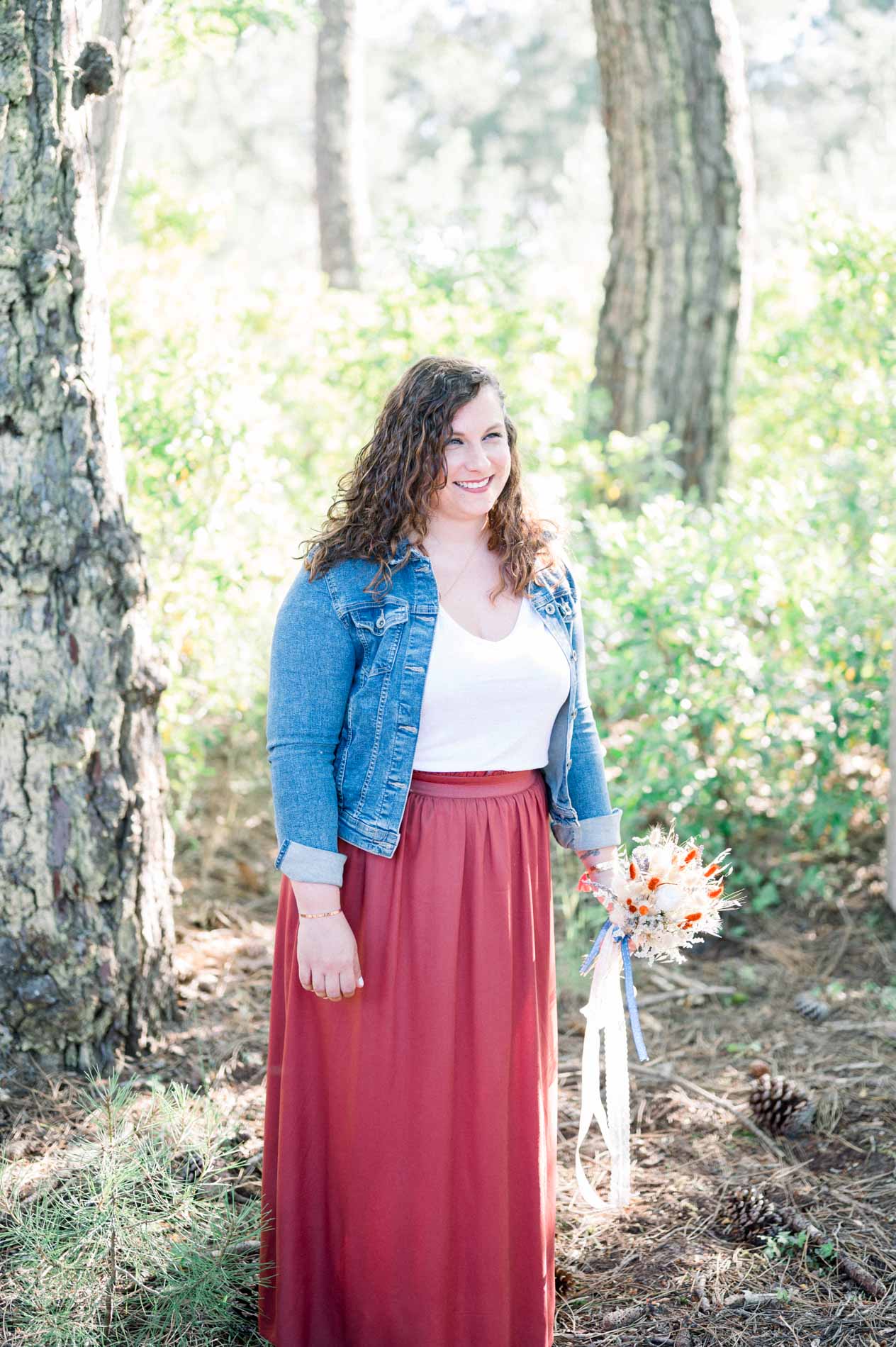 Young woman in a denim jacket and red skirt in the Cap Ferret pine forest