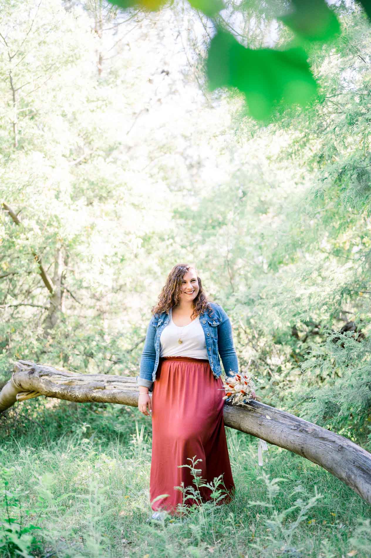 Young woman sitting on a fallen log amid lush greenery