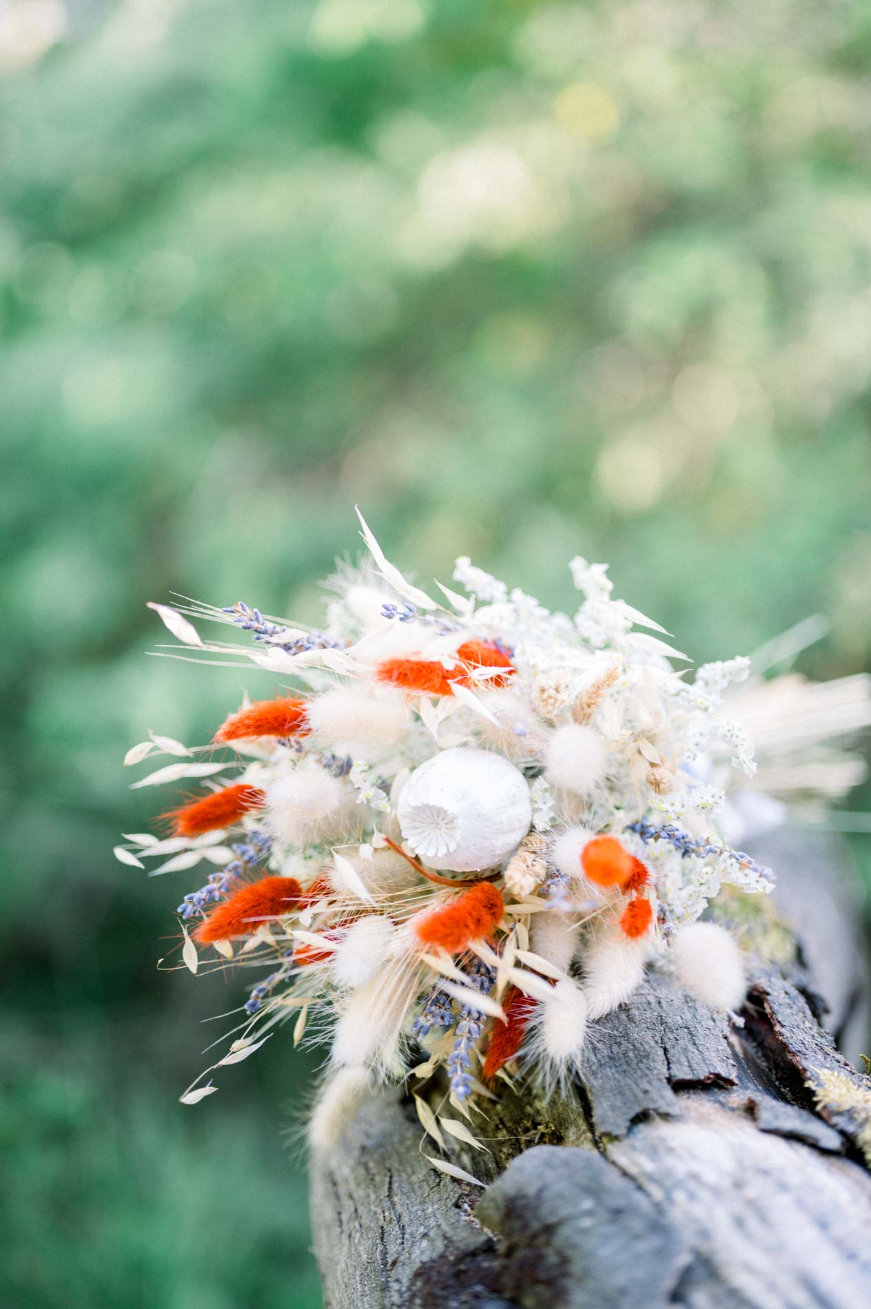 Dried flower bouquet on a tree stump against blurred greenery