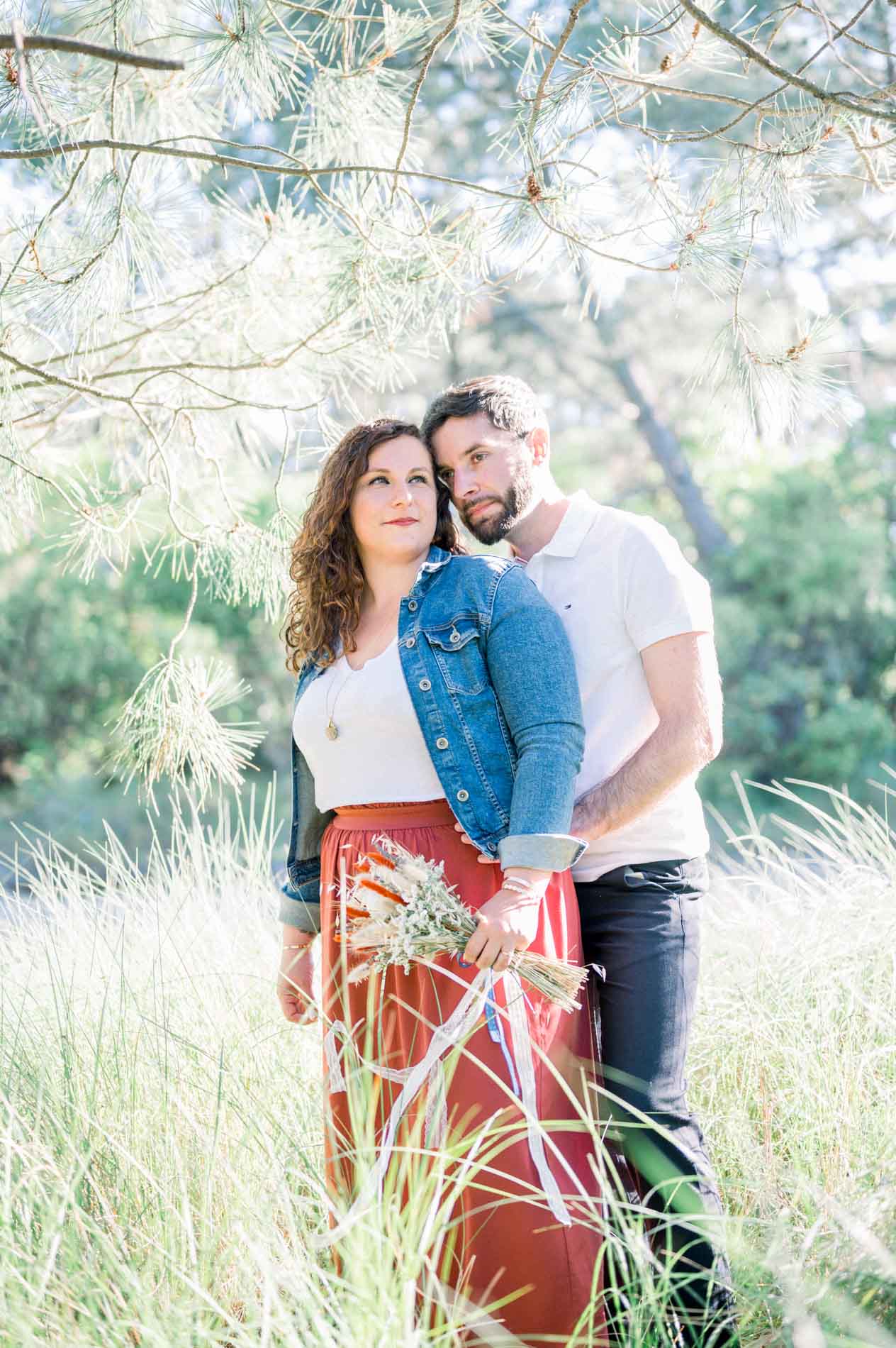 He hugs his partner from behind in the tall grass