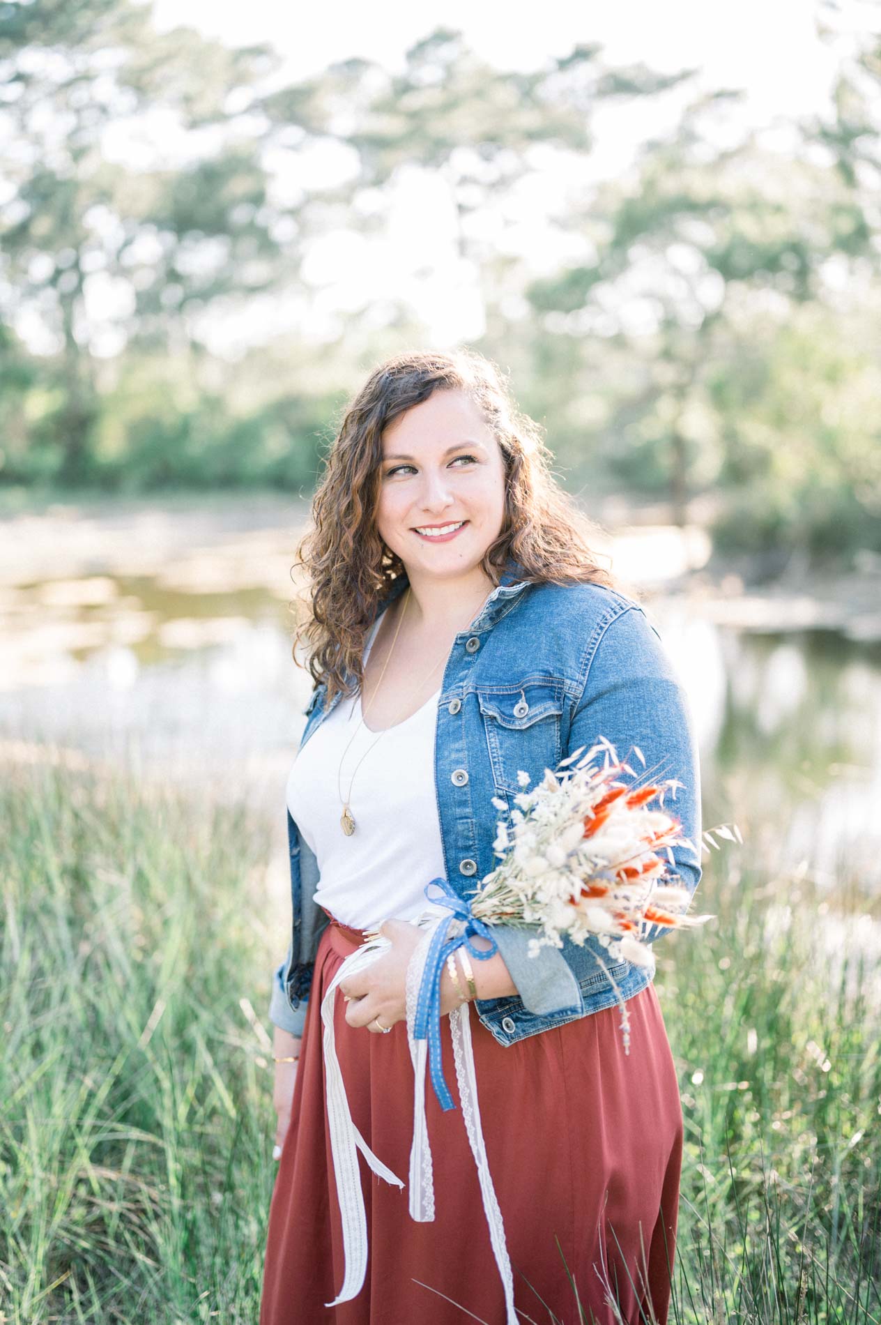 Smiling young woman holding her dried flower bouquet by the water