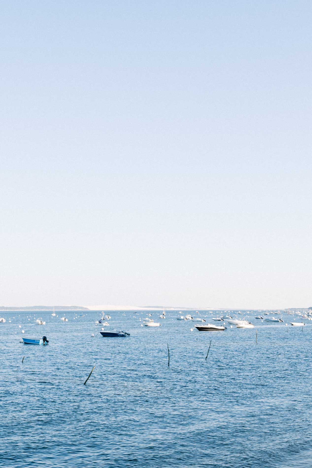 Boats moored on the blue waters of Arcachon Bay at Cap Ferret
