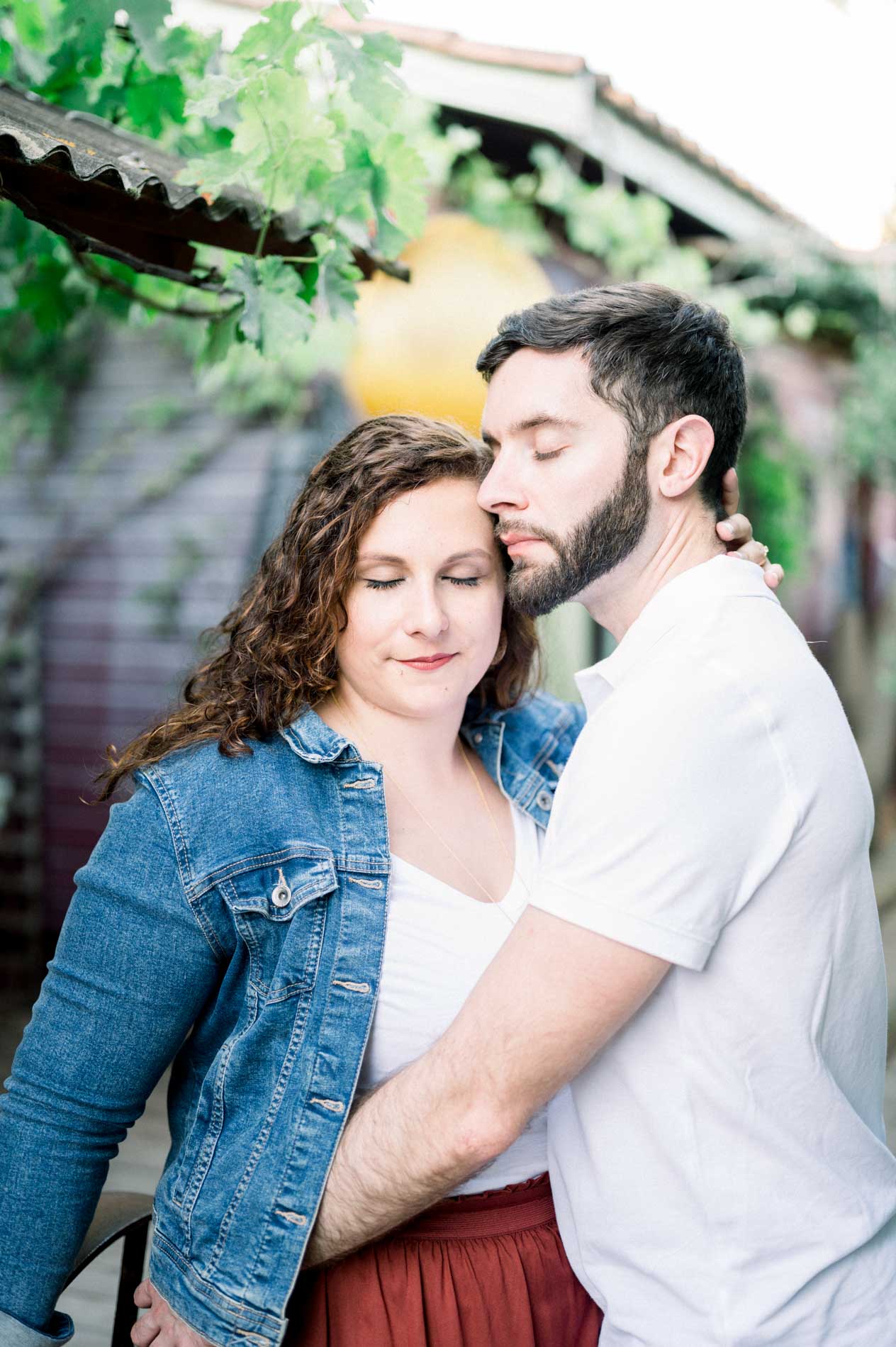 He kisses his partner's temple beneath a vine arbour in Le Canon
