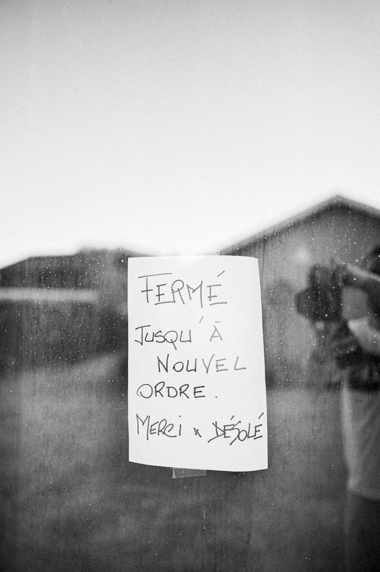 "Closed until further notice" sign in a window, black and white