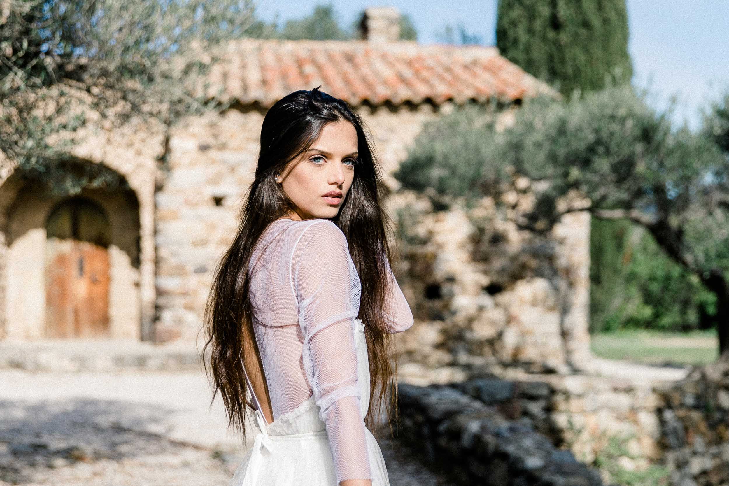 Woman in a light dress in front of an old stone house, fine art session