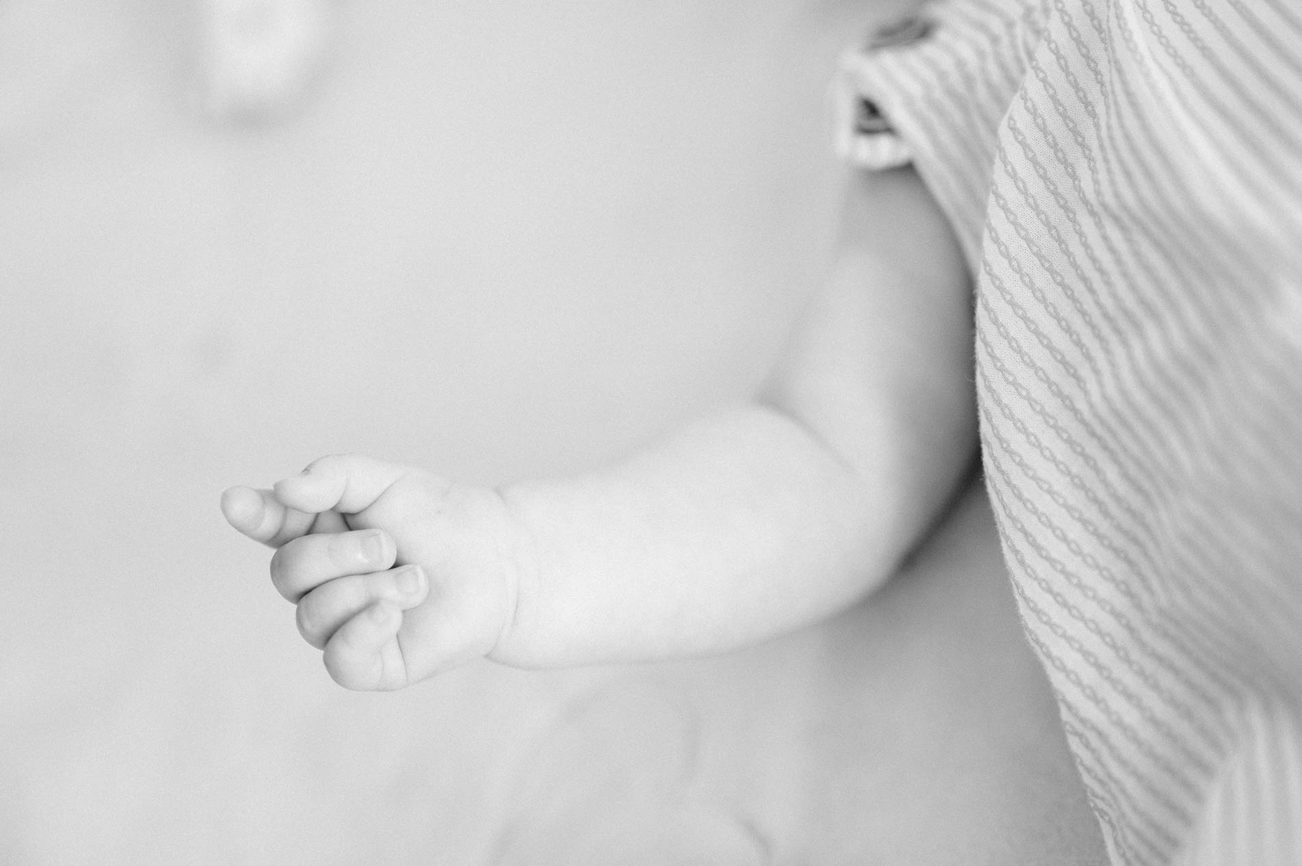 A baby's little hand reaching out on a blanket, in black and white
