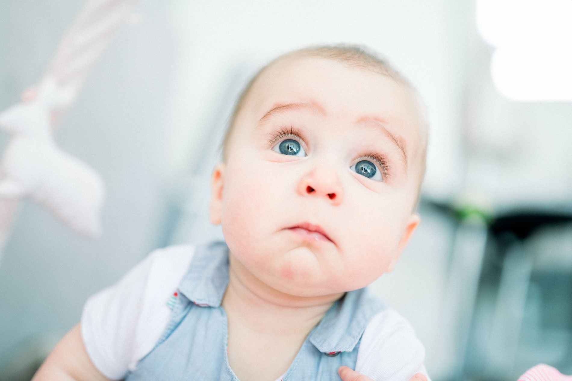 Close-up of a baby with big blue eyes lifting his head
