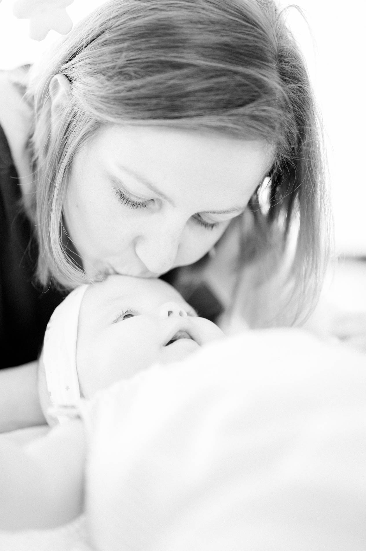 Mum kissing her baby's forehead, in black and white