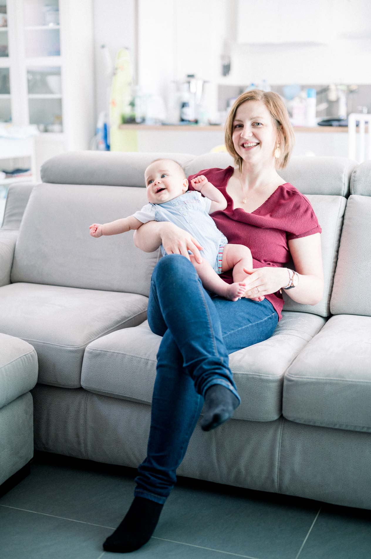 Smiling mum sitting on the sofa with her baby on her lap