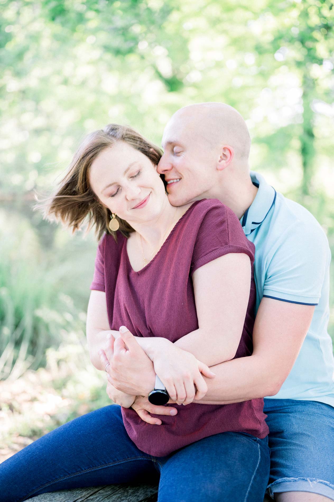 Parents embracing and smiling under the trees of Parc de Majolan