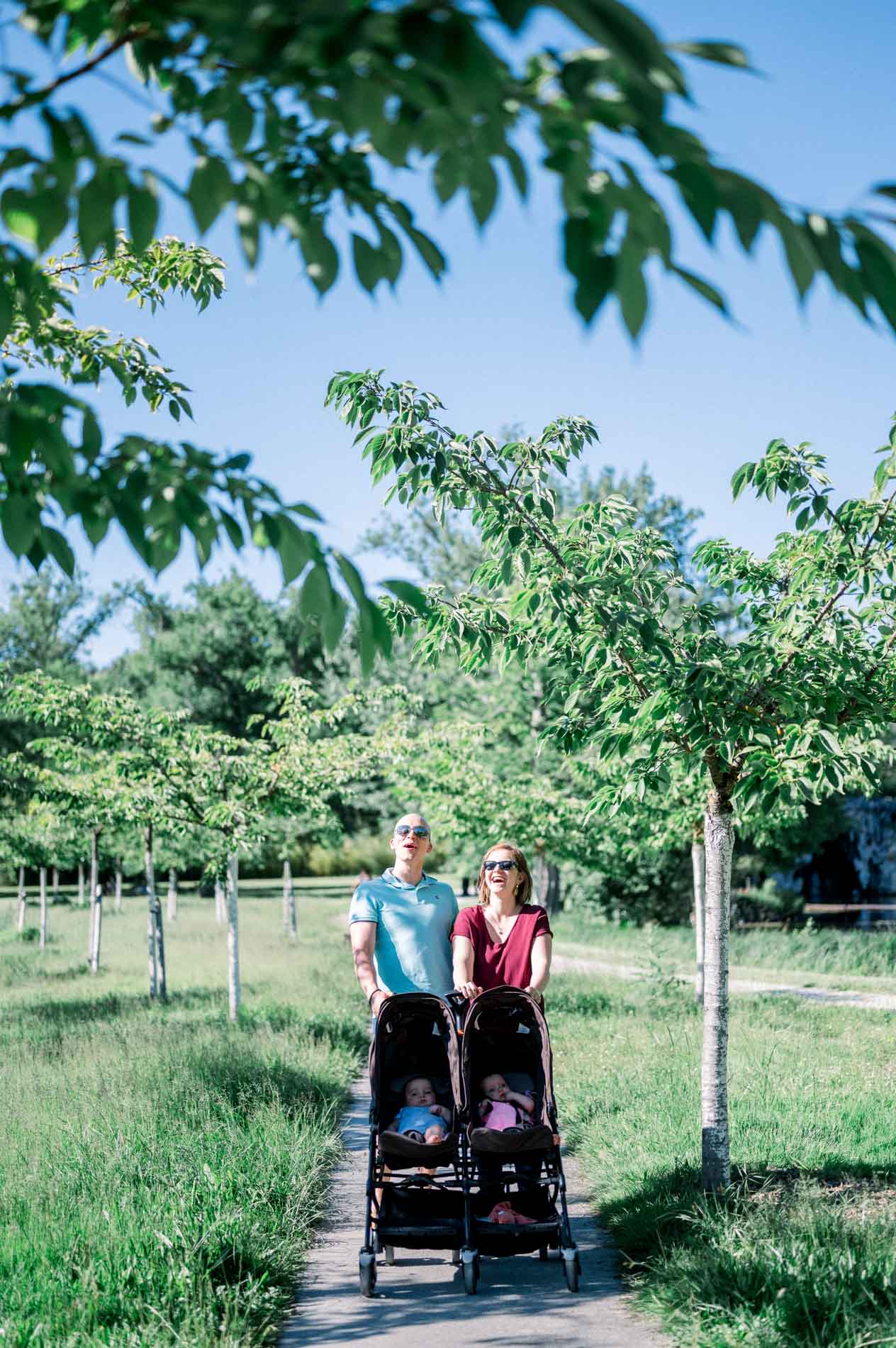 Parents pushing a double pushchair along a path in Parc de Majolan