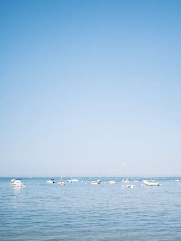 Boats moored on the calm waters of Arcachon Bay under a blue sky