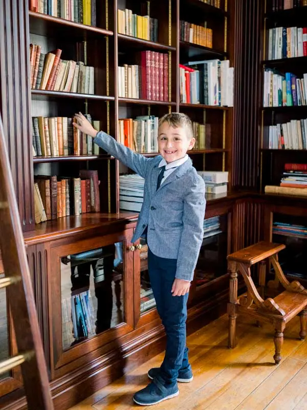 One of the couple's children in a grey suit in the villa's library