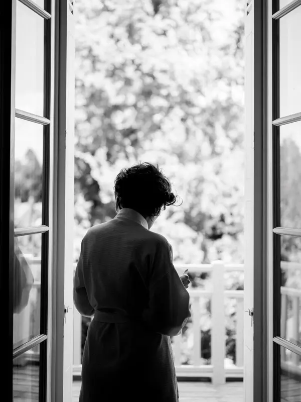 Black and white silhouette of the bride in her robe at an open French window