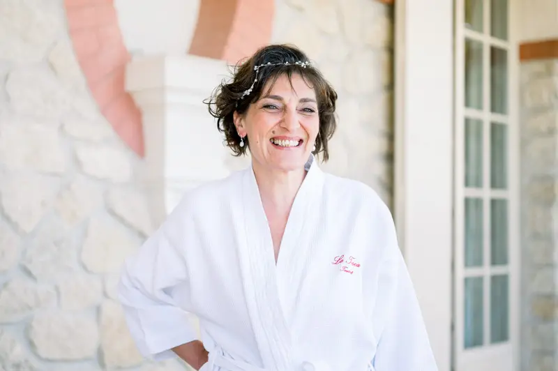The bride in her robe, tiara in her hair, laughing while getting ready