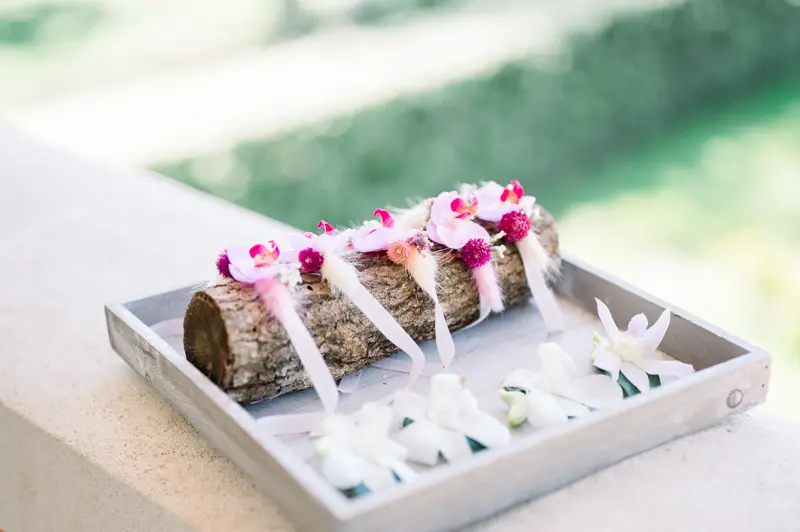 Pink and white flower boutonnieres arranged on a log in a tray