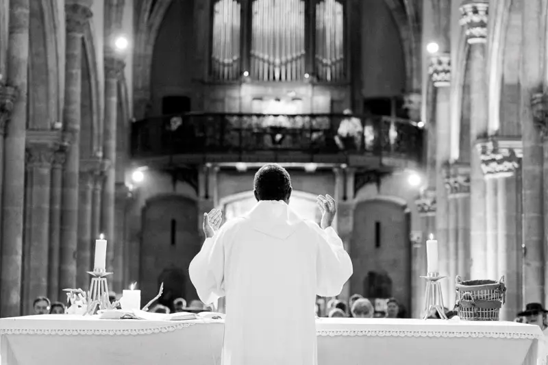 Black and white shot of the priest celebrating the wedding mass facing the organ