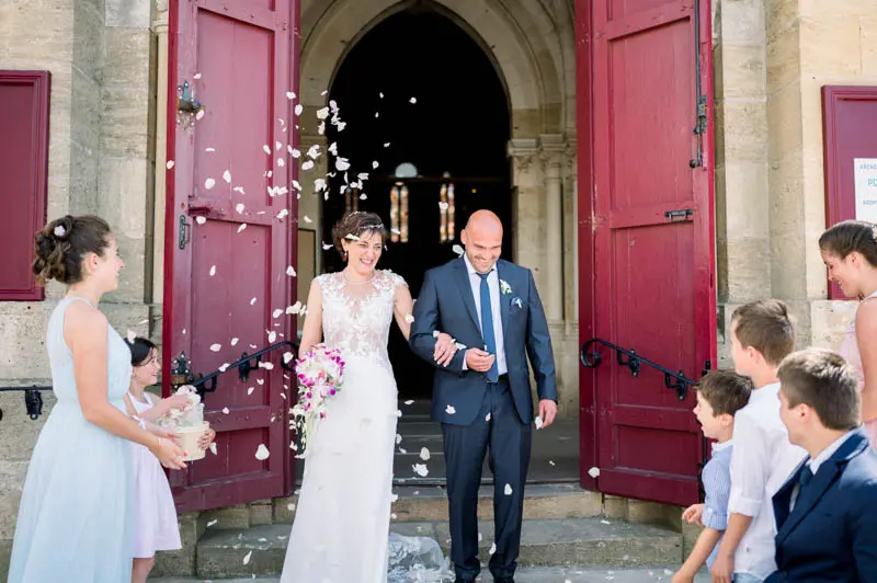 The newlyweds leave the church under a shower of petals by its red doors