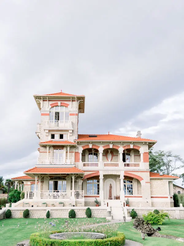 Villa La Tosca and its tower under a cloudy sky, seen from the garden