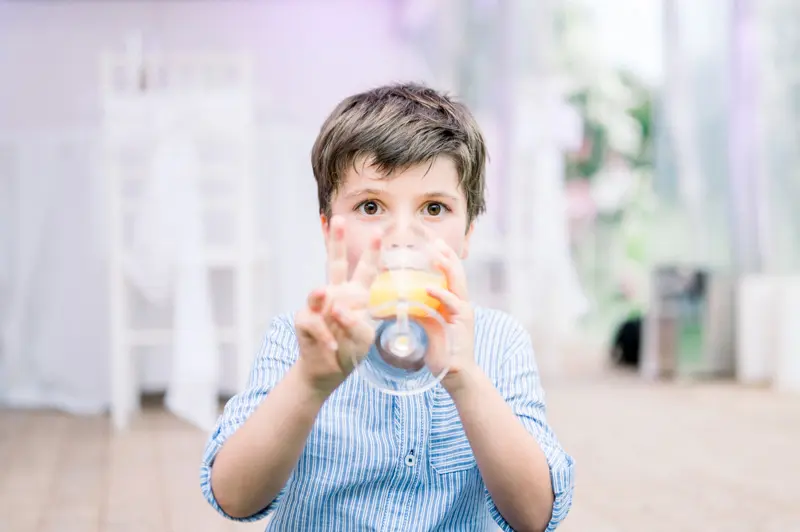 One of the couple's children drinking a glass of juice in the marquee