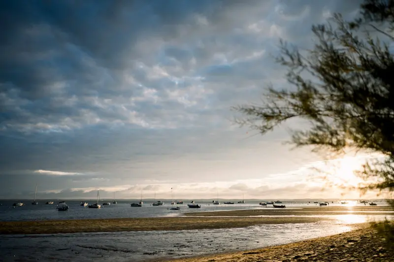 Sunset over Arcachon Bay at low tide with boats at anchor